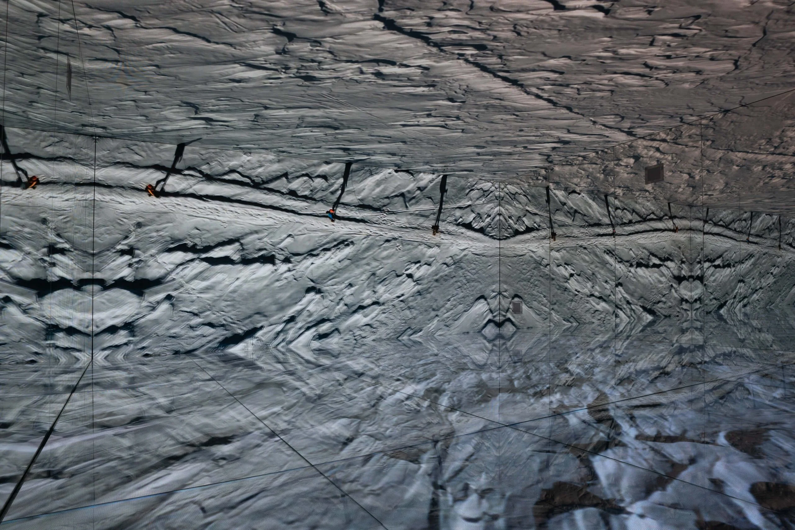 Aerial footage of snow-covered rock ridges on the LED ceiling and walls, mirrored into a symmetrical pattern – Mont Blanc Infinity Room at Skyway, Courmayeur, Italy, 2023 – installation design
