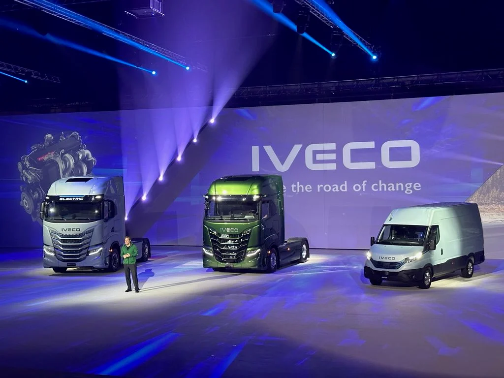 Presenter on stage beside two trucks and a van, the Iveco logo on the LED backdrop – IVECO Be The Change Launch, Barcelona, Spain, 2023 – event design