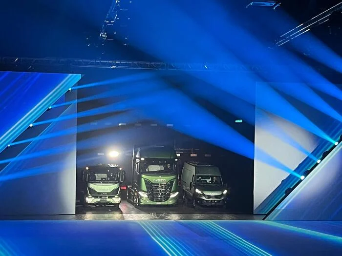 Three green Iveco vehicles emerging through an opening in the LED wall under blue beams – IVECO Be The Change Launch, Barcelona, Spain, 2023 – event design