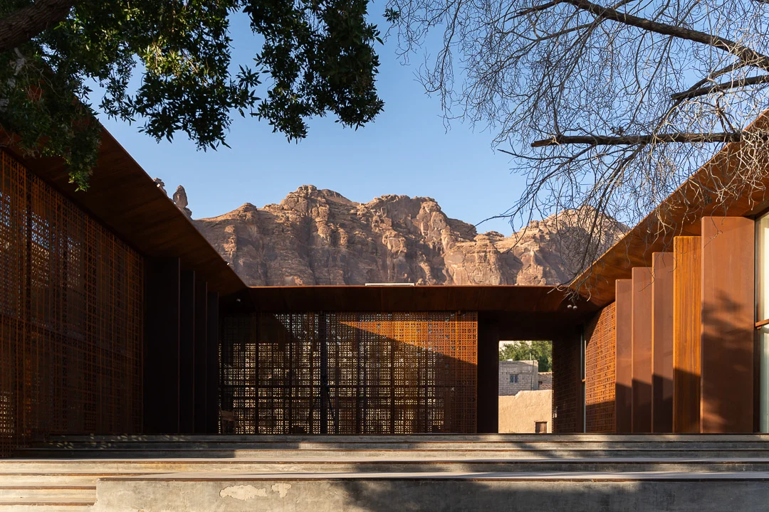 Courtyard framed by rust-coloured metal screens and fins, with AlUla's rocky cliffs behind – Design Space AlUla, Saudi Arabia, 2024 – architecture