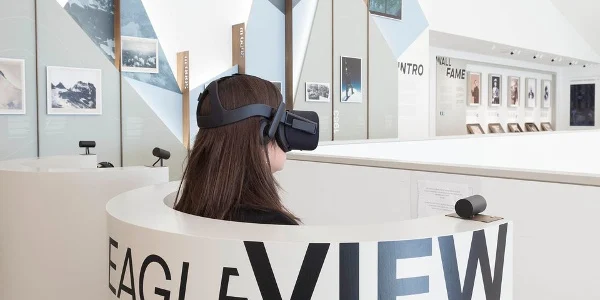 Visitor wearing a VR headset in the curved Eagle View booth, with photo exhibits on the walls behind – Lumen Museum of Mountain Photography, Kronplatz, Italy, 2018 – architecture