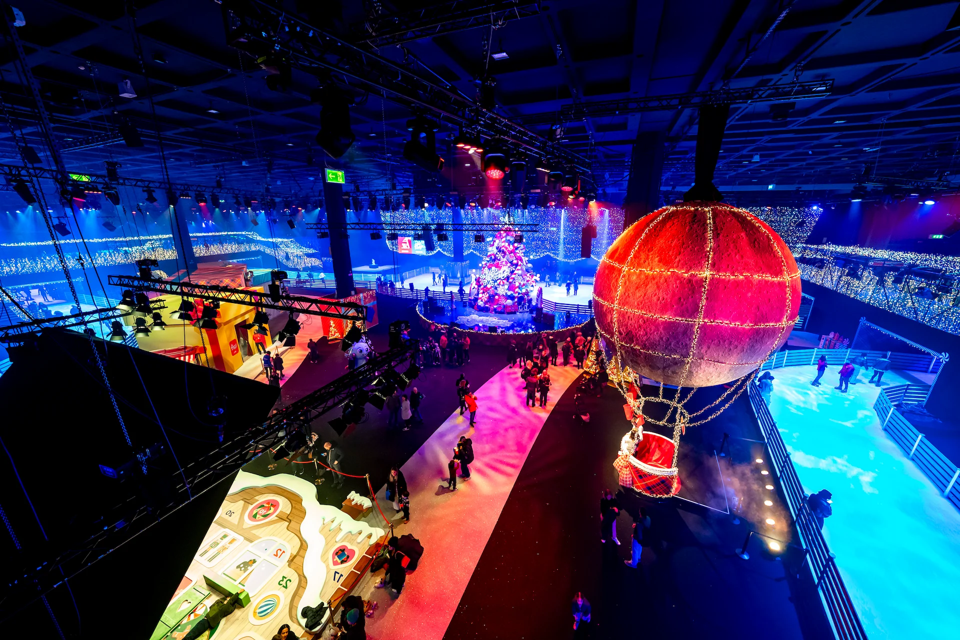 Aerial view of the hall with a lit hot-air balloon, the ice rink, the Christmas tree and visitors – A Christmas Magic at Allianz MiCo, Milan, Italy, 2023 – event design