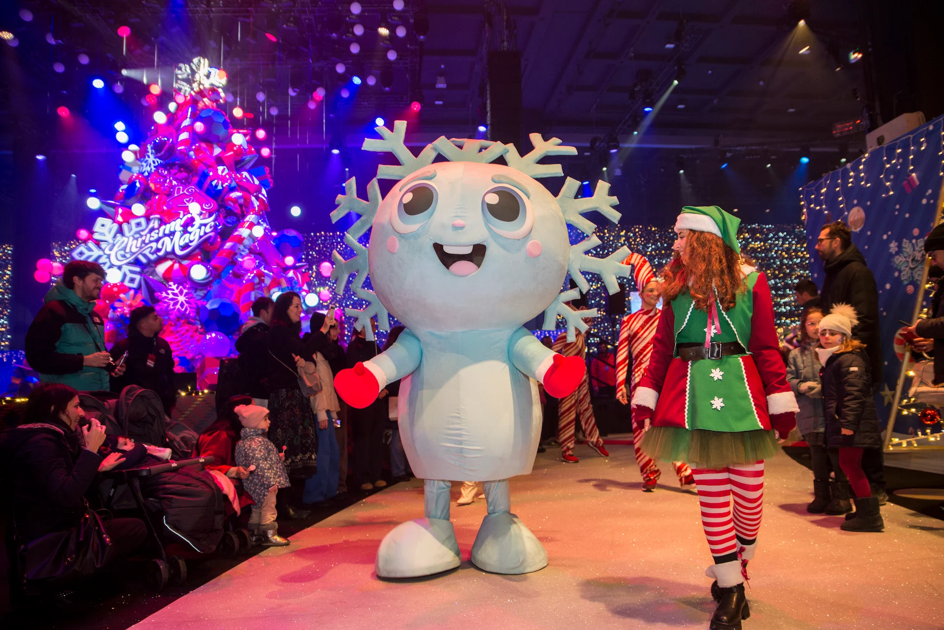 Snowflake mascot and an elf parading among families in front of the illuminated Christmas tree – A Christmas Magic at Allianz MiCo, Milan, Italy, 2023 – event design