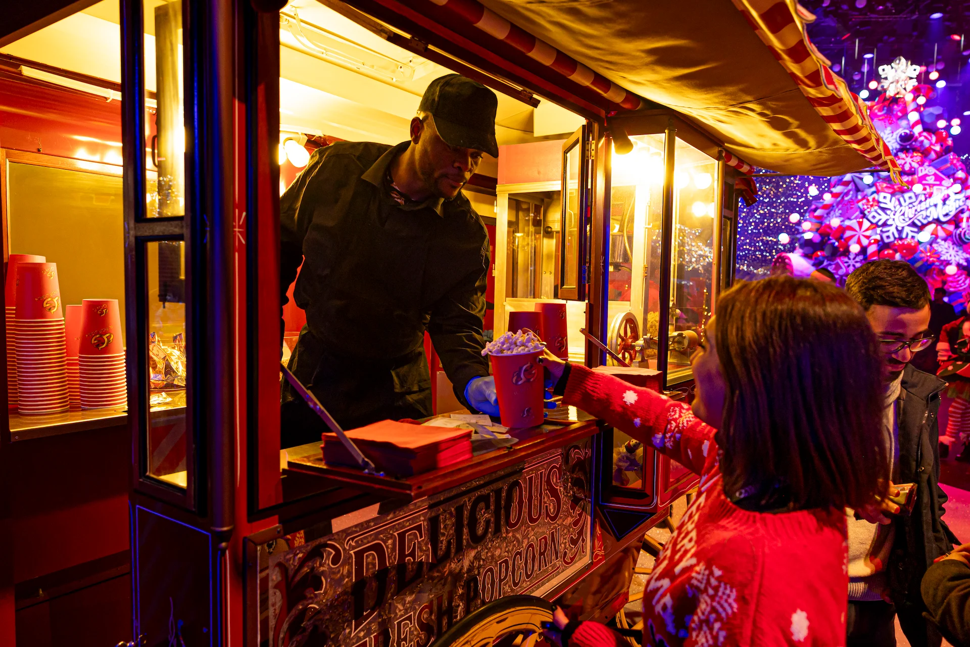 Vendor serving popcorn from a red vintage cart to visitors in Christmas sweaters – A Christmas Magic at Allianz MiCo, Milan, Italy, 2023 – event design
