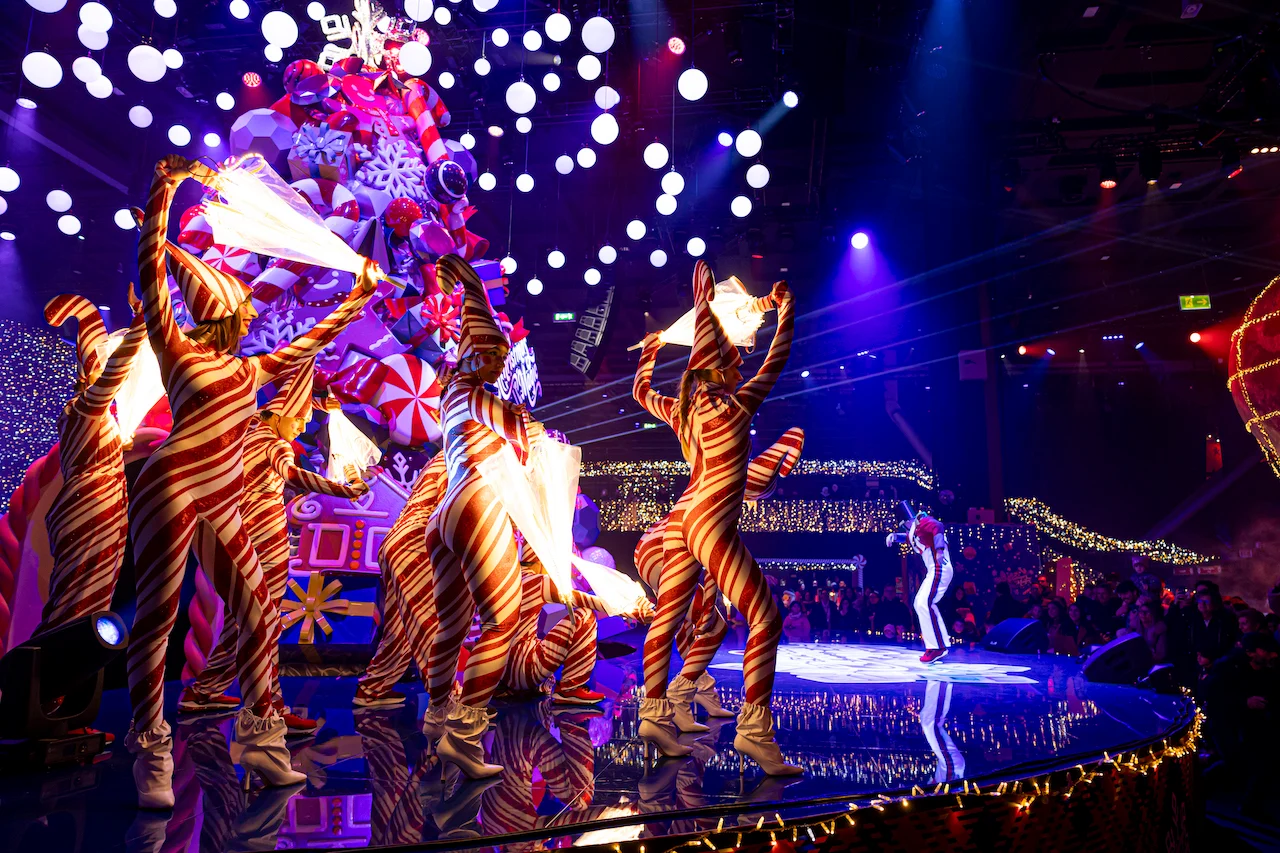 Dancers in red-and-white striped candy cane costumes performing on a round stage before the tree – A Christmas Magic at Allianz MiCo, Milan, Italy, 2023 – event design
