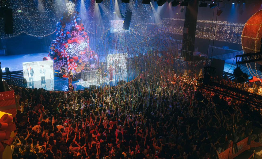 Packed crowd under falling streamers in front of a giant decorated Christmas tree and stage screens – A Christmas Magic at Allianz MiCo, Milan, Italy, 2023 – event design