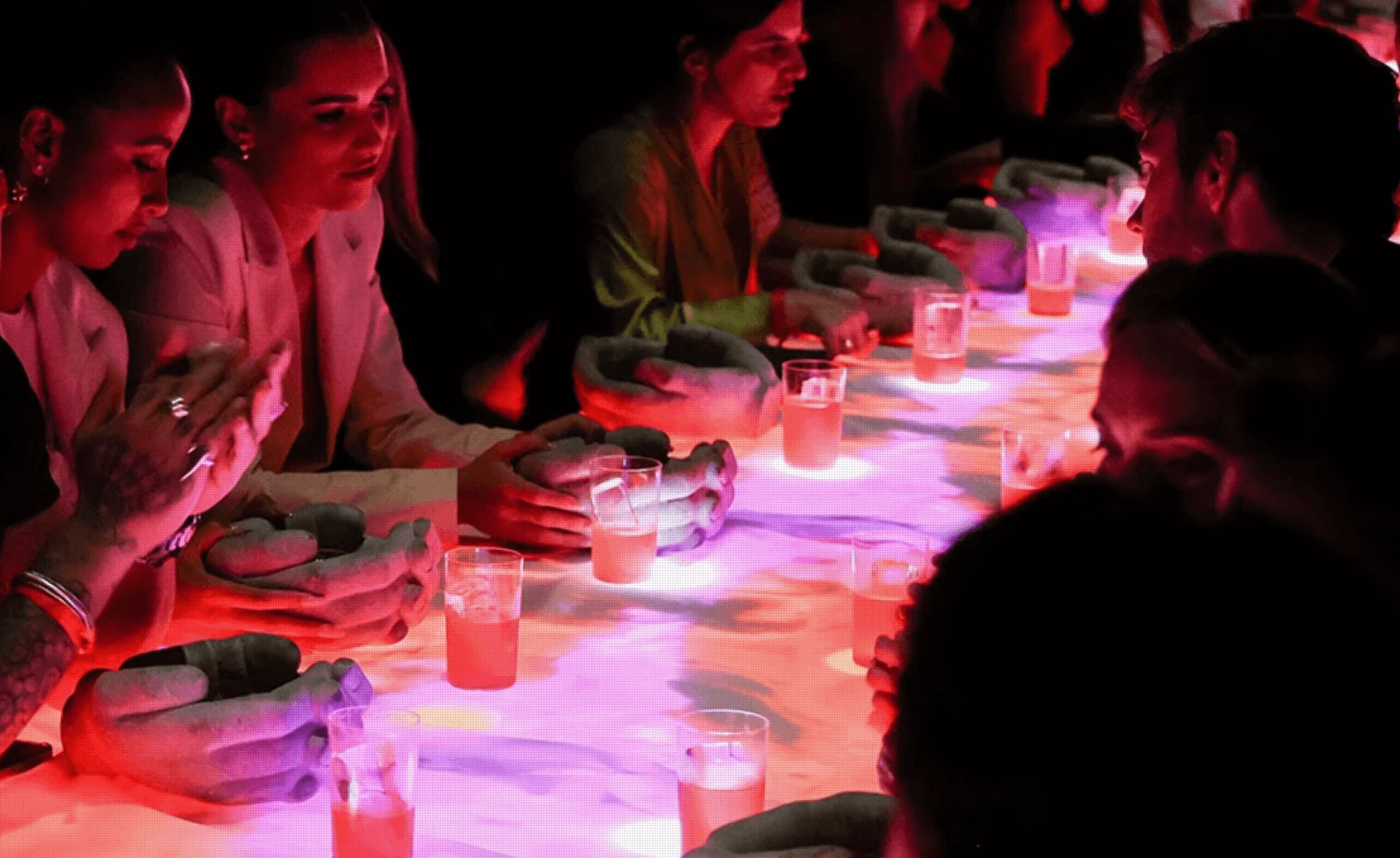 Close-up of guests at the LED table, hands resting by glowing projections and pink drinks – Campari Discover Red Party at Cannes Film Festival, France, 2023 – event design