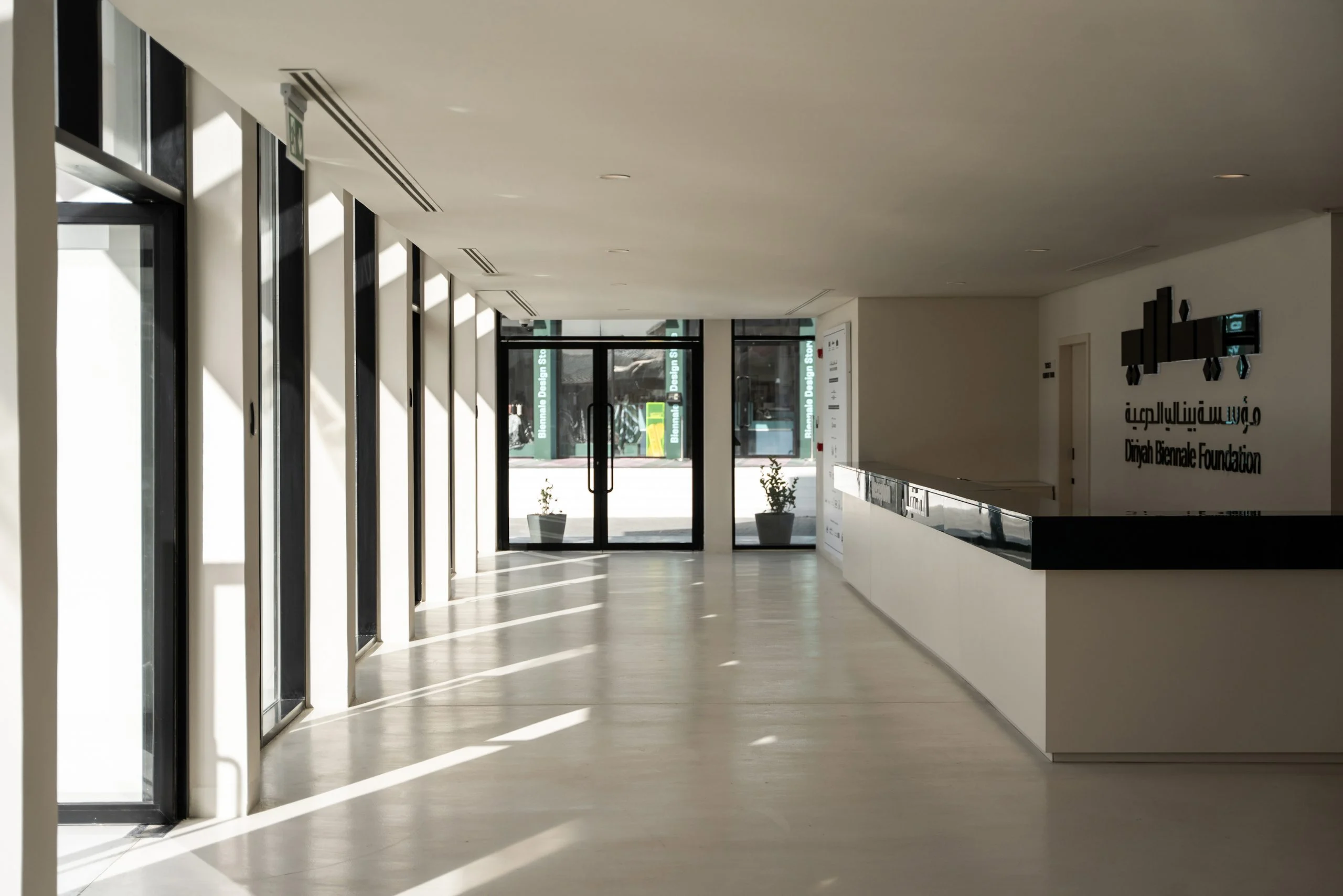 Sunlit reception hall with tall windows, a long white desk and the Diriyah Biennale Foundation logo – Diriyah Contemporary Art Biennale, Riyadh, Saudi Arabia, 2024 – architecture