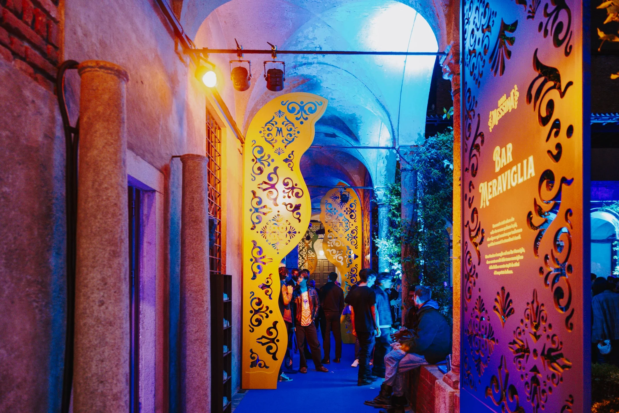 Vaulted arcade at night with golden cut-out panels, coloured lighting and a Bar Meraviglia sign – Birra Messina Bar Meraviglia at Fuorisalone, Milan, Italy, 2024 – event design