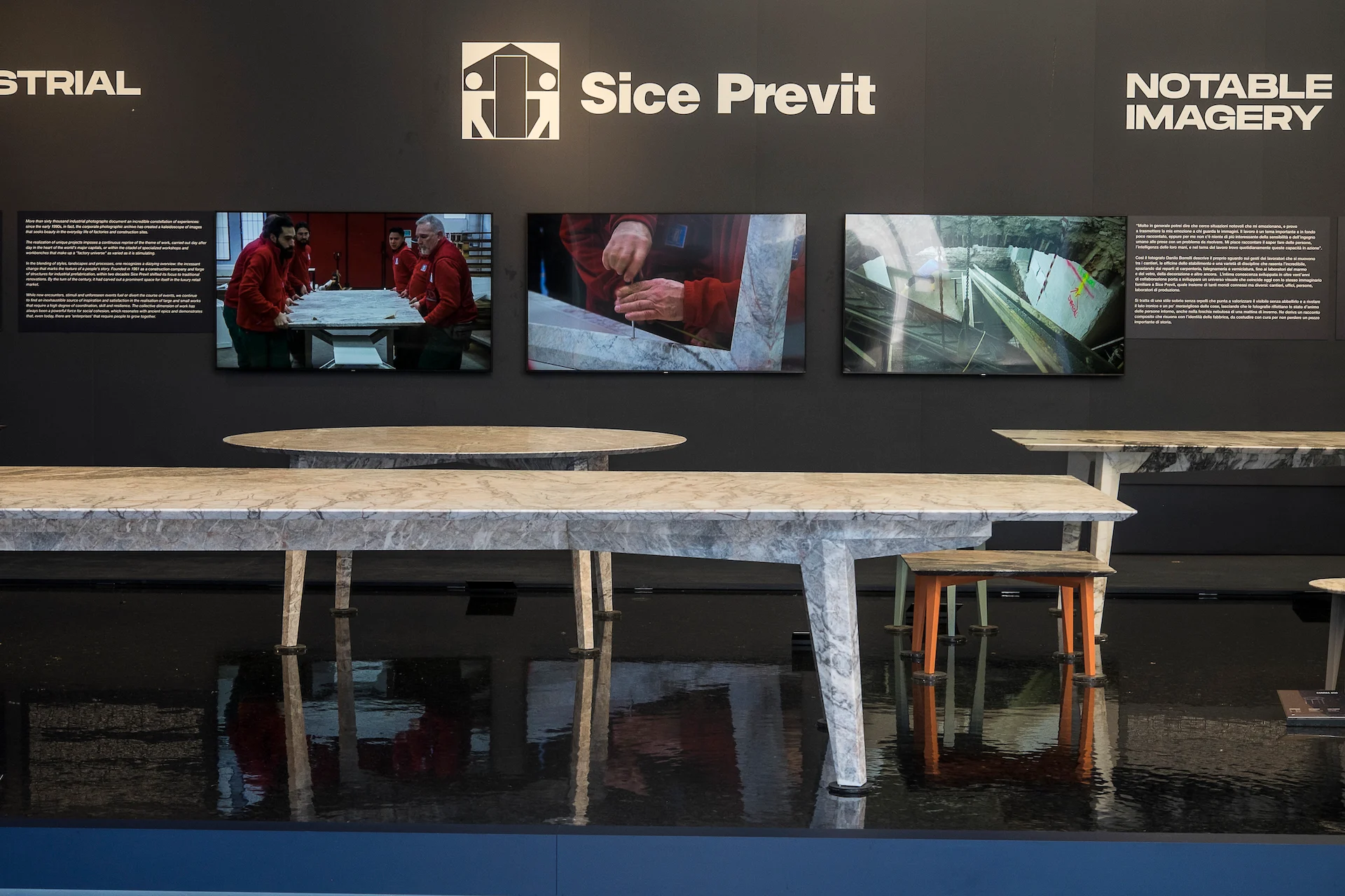 Sice Previt exhibition wall with video screens above marble-topped tables standing in a reflective black pool – Factory Reflections at Sice Previt, Segrate, Italy, 2024 – exhibition design