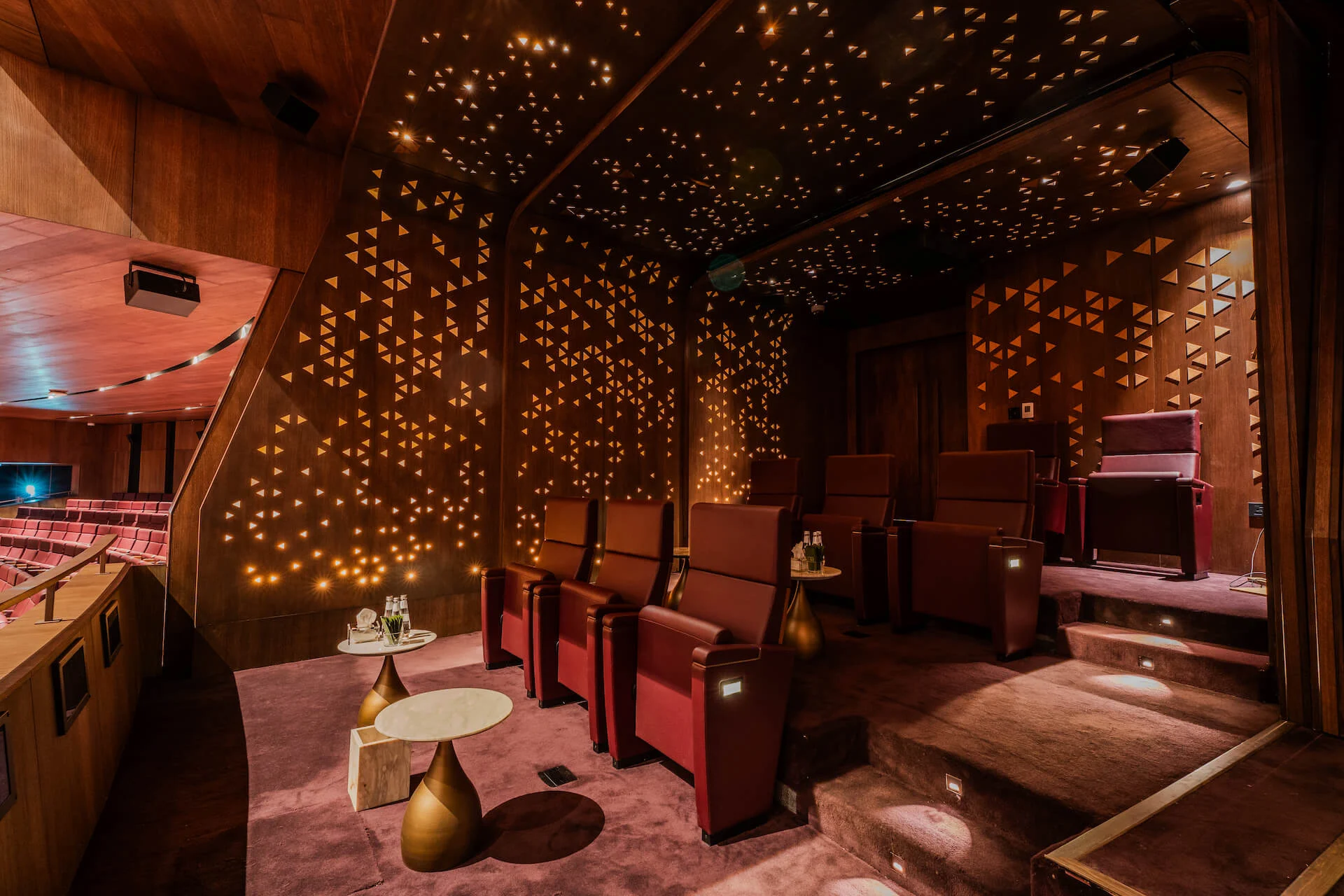 Private theatre box with red armchairs, small brass tables and wood walls perforated with glowing triangles – King Fahad Cultural Center, Riyadh, Saudi Arabia, 2024 – architectural renovation