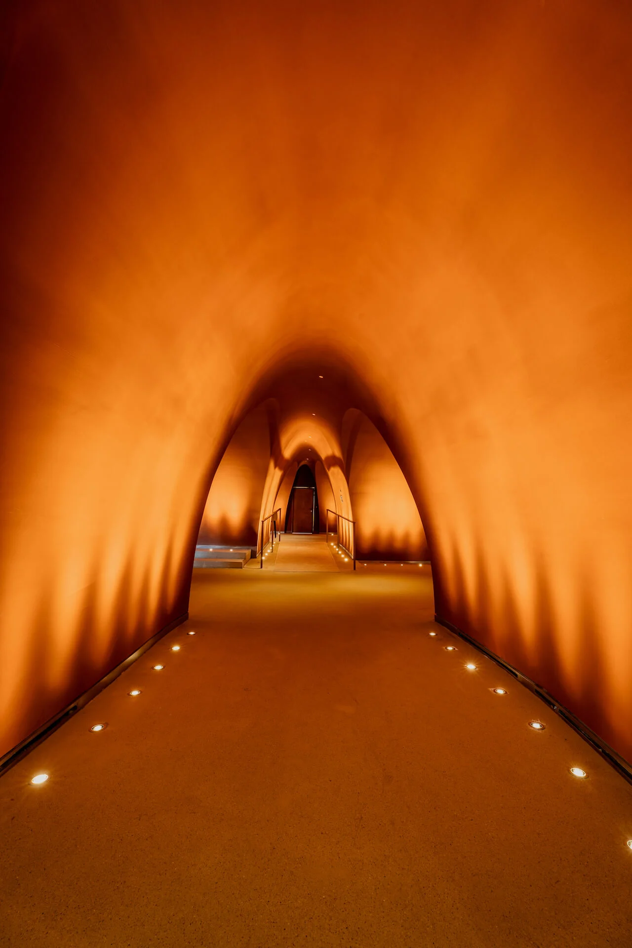 Arched orange-lit corridor with floor lights leading to a distant doorway – King Fahad Cultural Center, Riyadh, Saudi Arabia, 2024 – architectural renovation