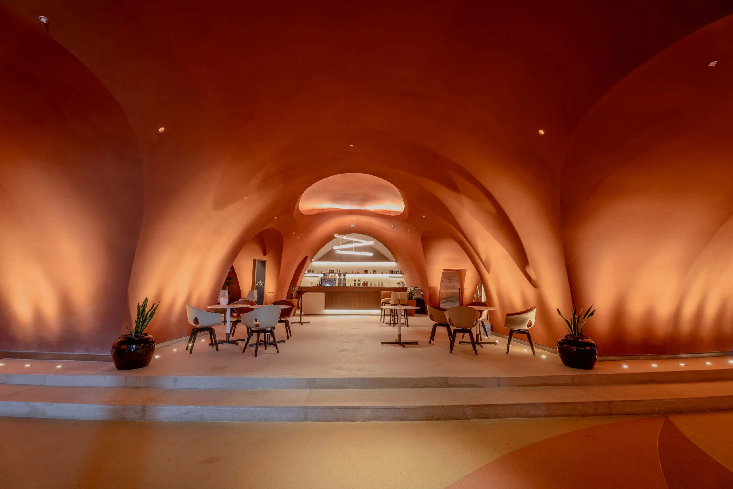 Café under organic terracotta vaults, with chairs and tables leading to a backlit counter – King Fahad Cultural Center, Riyadh, Saudi Arabia, 2024 – architectural renovation