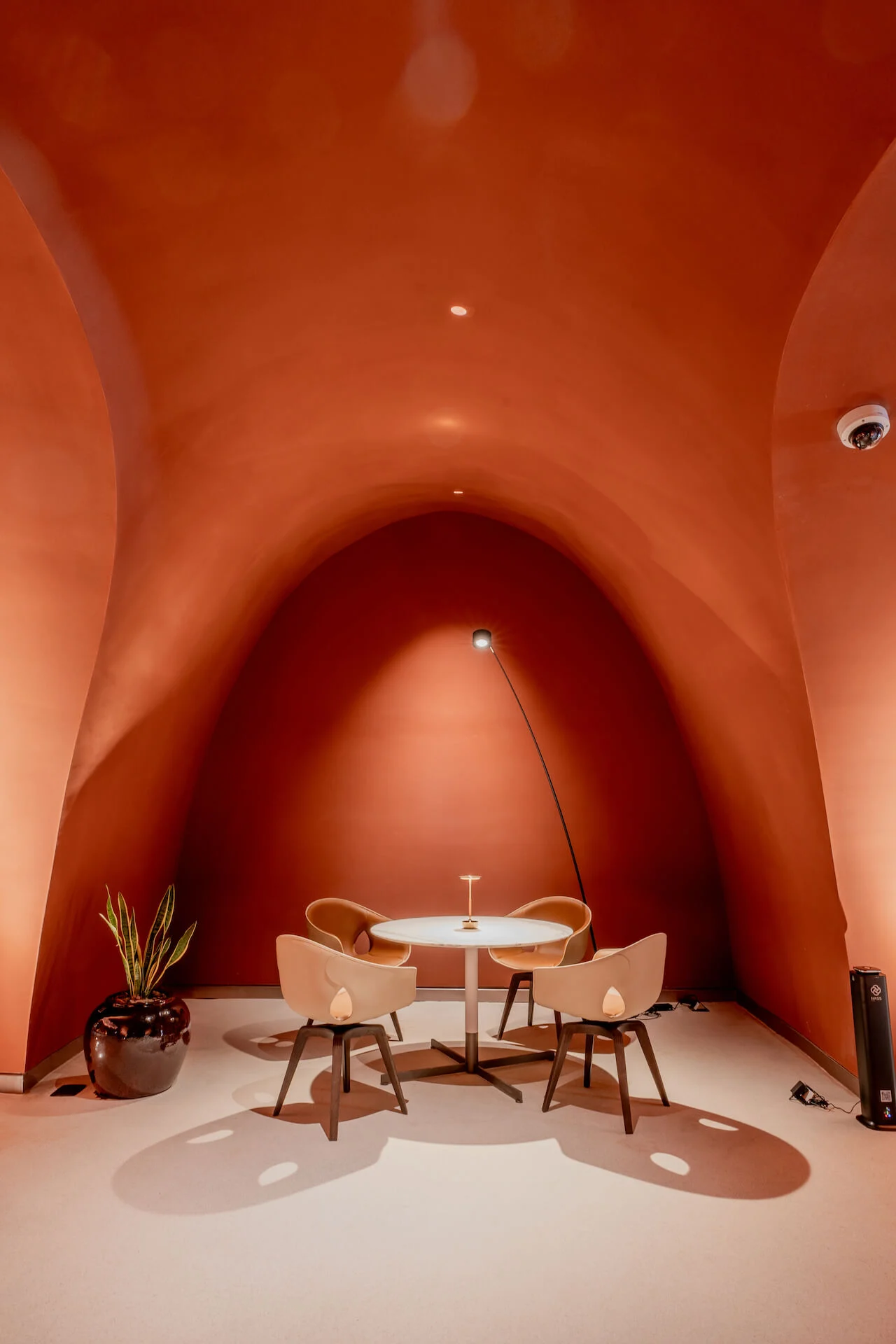 Small round table with four chairs and an arc floor lamp inside a terracotta vaulted alcove – King Fahad Cultural Center, Riyadh, Saudi Arabia, 2024 – architectural renovation