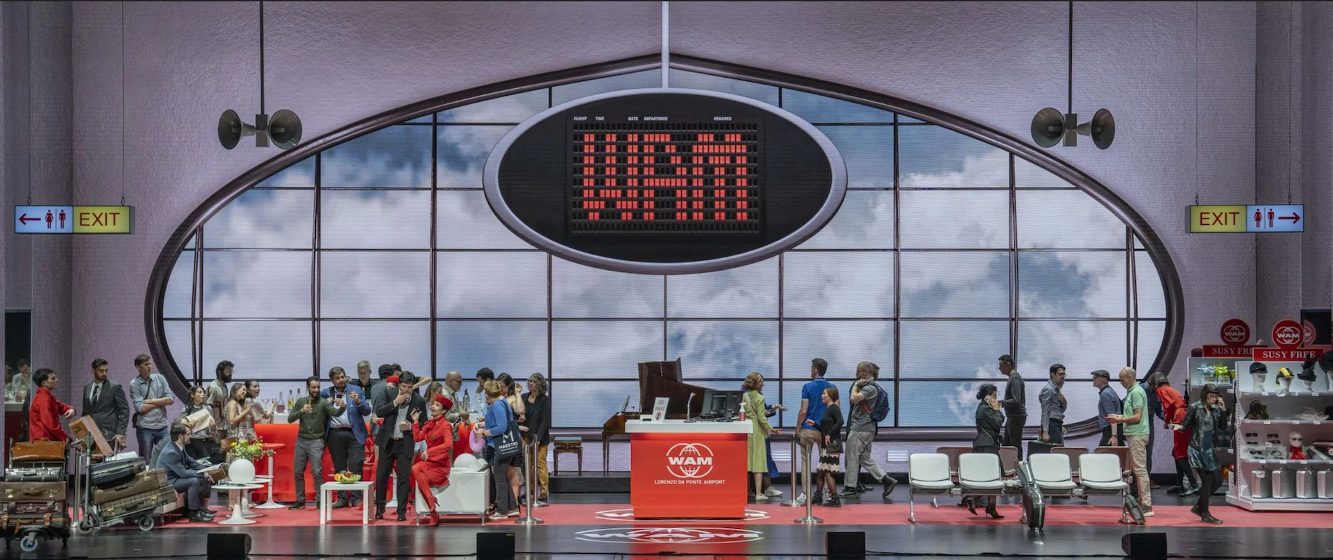 Airport set with a red flight information board over the oval window and passengers waiting – Une Folle Journée Mozart Gala, Salzburg, Austria, 2024 – opera set design