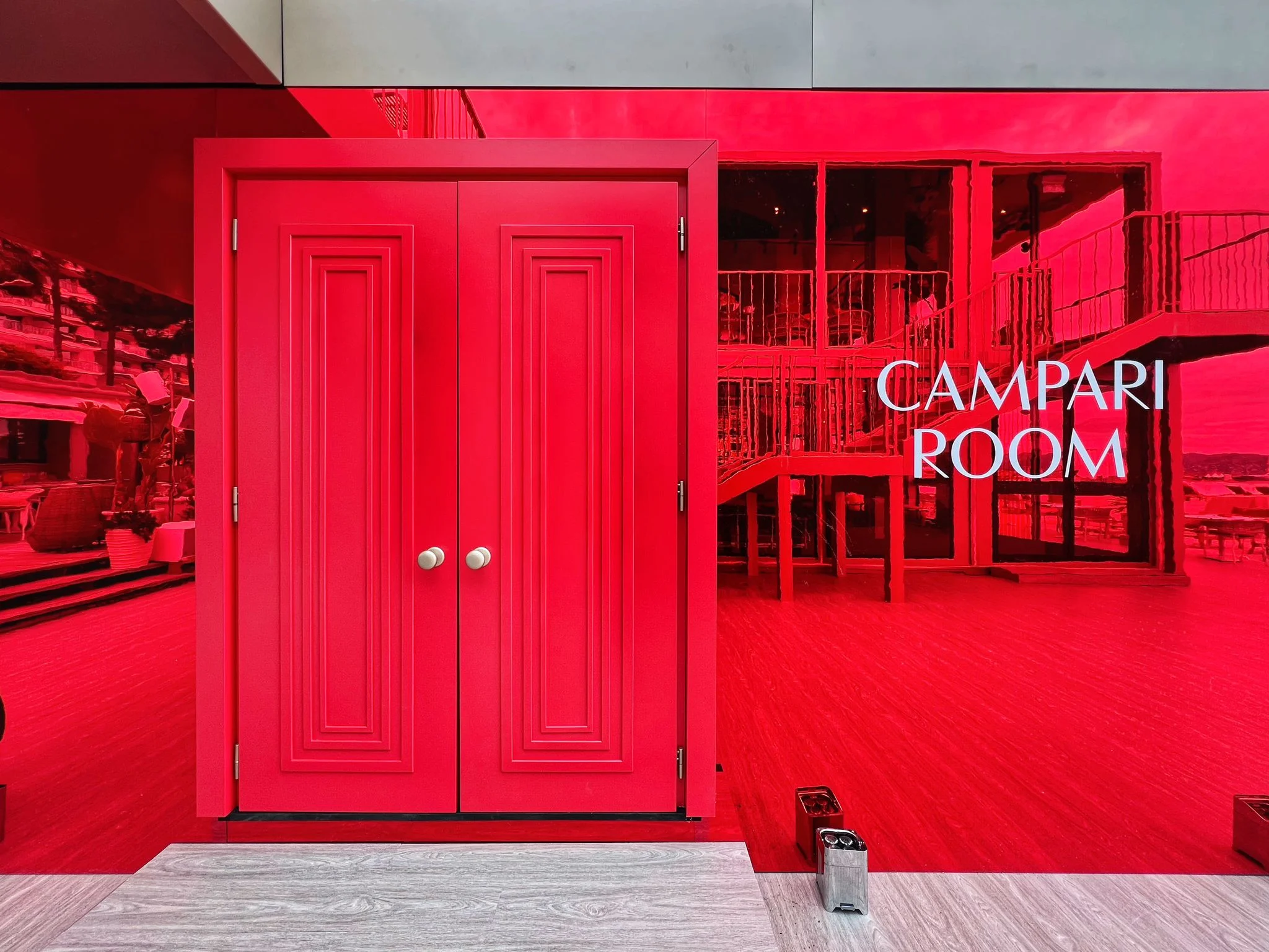 Red double doors set into a red mirrored wall with Campari Room lettering – Campari Cannes Film Festival 2024, France – event architecture
