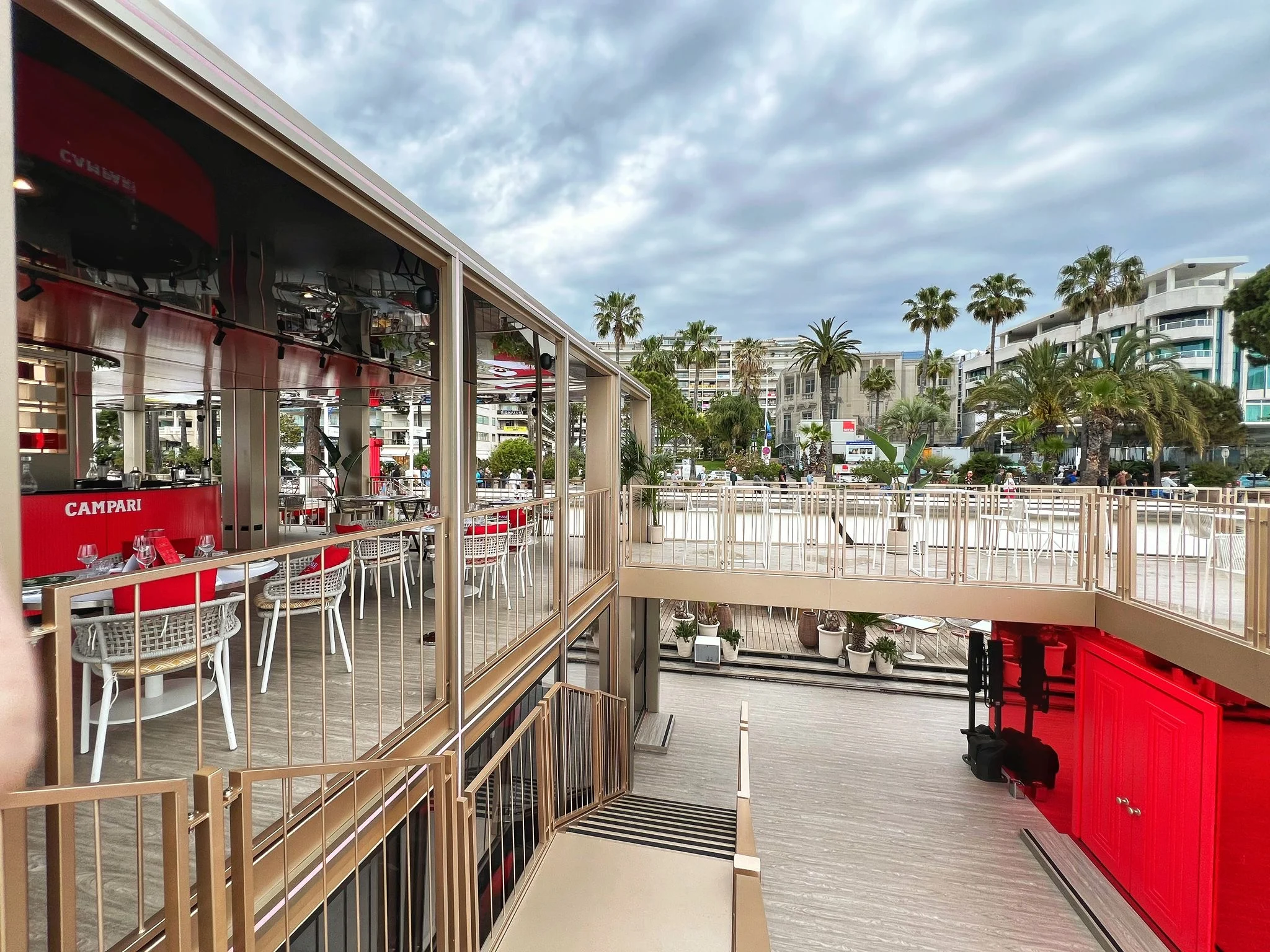 Upper terrace of the Campari pavilion overlooking the palm trees and buildings of the Croisette – Campari Cannes Film Festival 2024, France – event architecture
