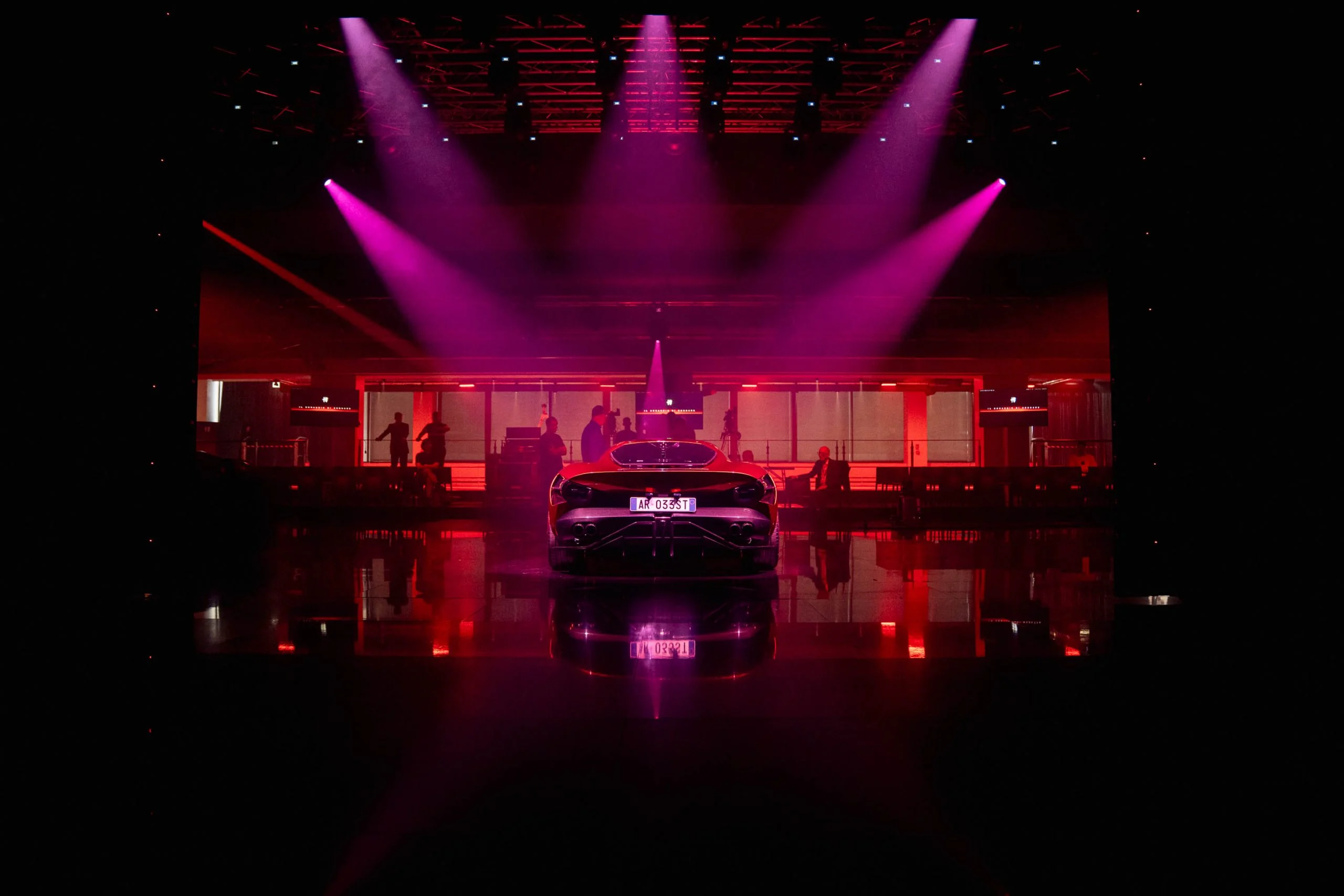 Rear view of the new car under magenta spotlights, centred on a reflective floor – Alfa Romeo 33 Stradale Unveiling, Arese, Italy, 2023 – event design