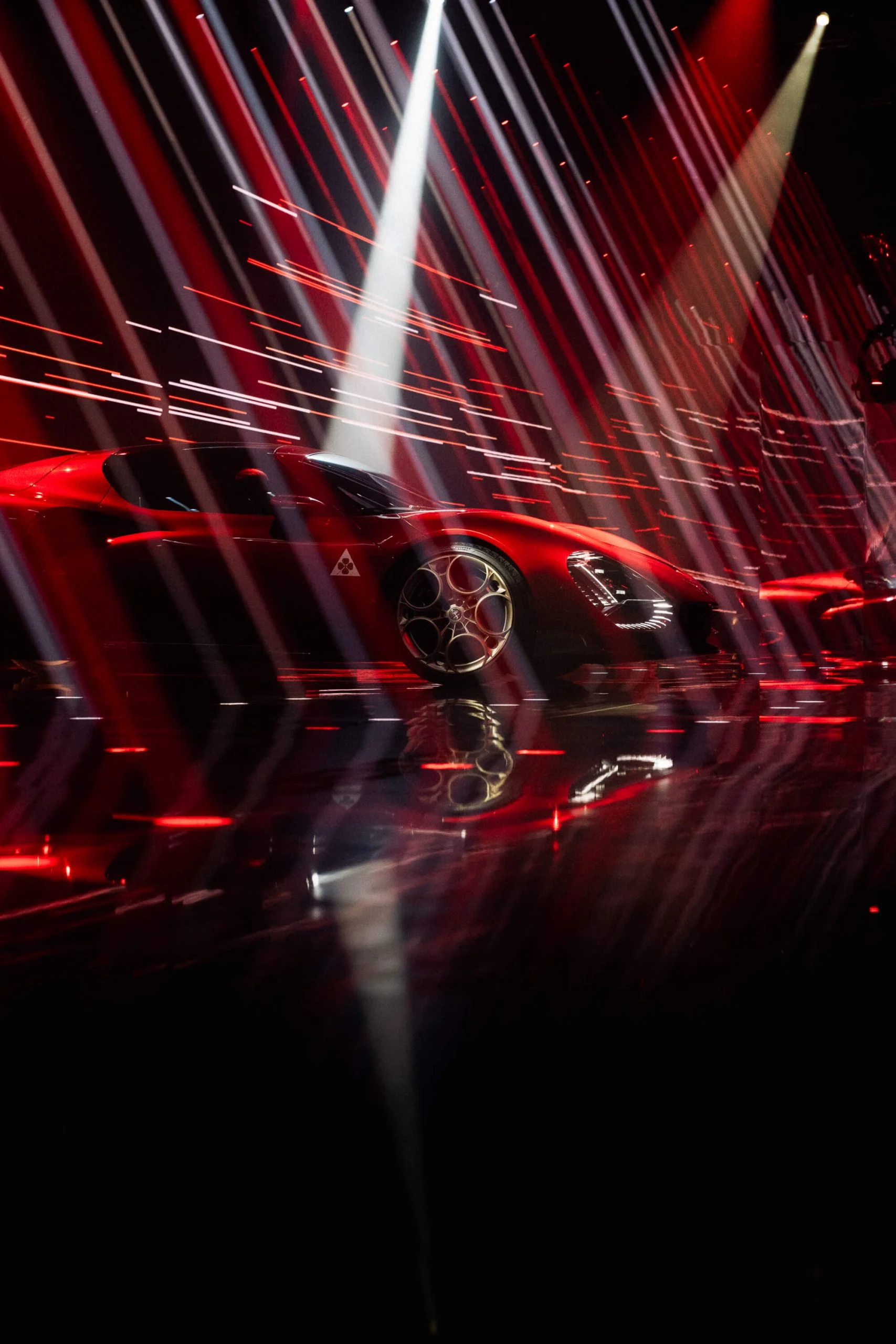 Side of the red car crossed by streaks of white and red light, reflected in a glossy floor – Alfa Romeo 33 Stradale Unveiling, Arese, Italy, 2023 – event design