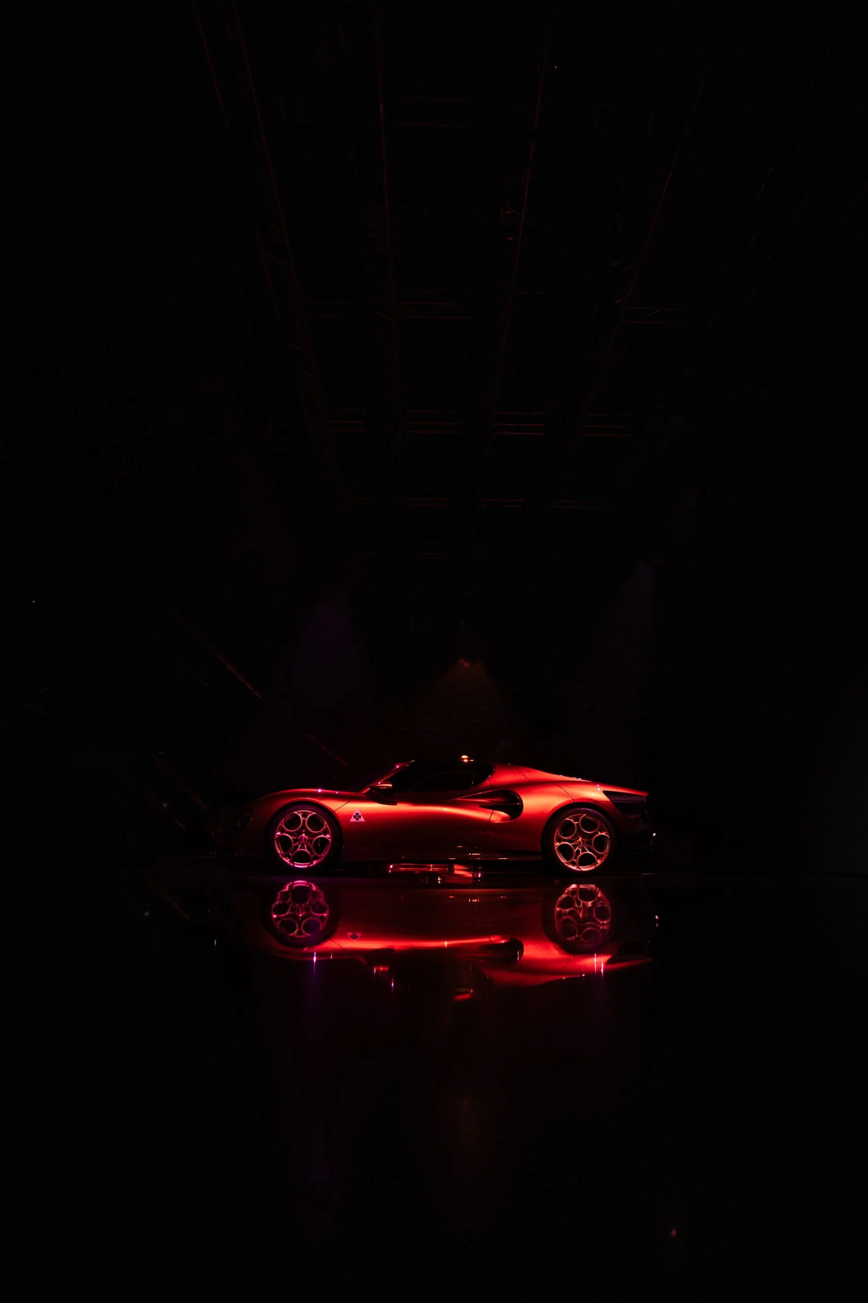 Red 33 Stradale in profile, alone in a dark space and mirrored on the floor – Alfa Romeo 33 Stradale Unveiling, Arese, Italy, 2023 – event design