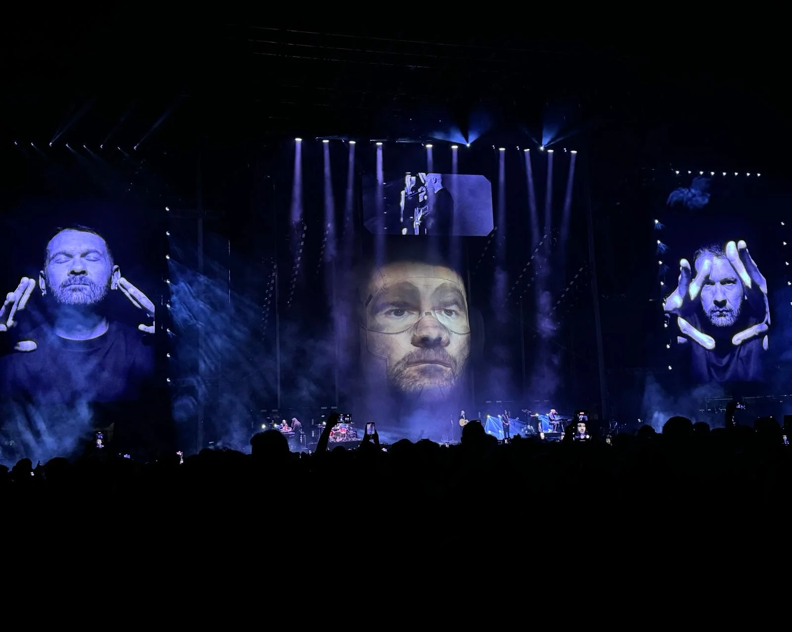 Stage in blue light with a face projected onto the giant head and close-ups on the side screens – Negramaro Stadi 2024, Italy – concert stage design
