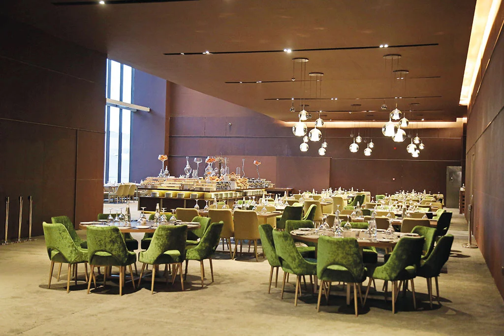 Banquet room with green velvet chairs, set round tables and glass pendant lights – Maraya Concert Hall, AlUla, Saudi Arabia, 2019 – architecture