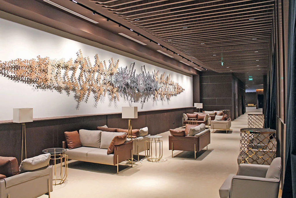 Lounge with leather sofas, gold side tables and a long metal wall sculpture under a slatted ceiling – Maraya Concert Hall, AlUla, Saudi Arabia, 2019 – architecture