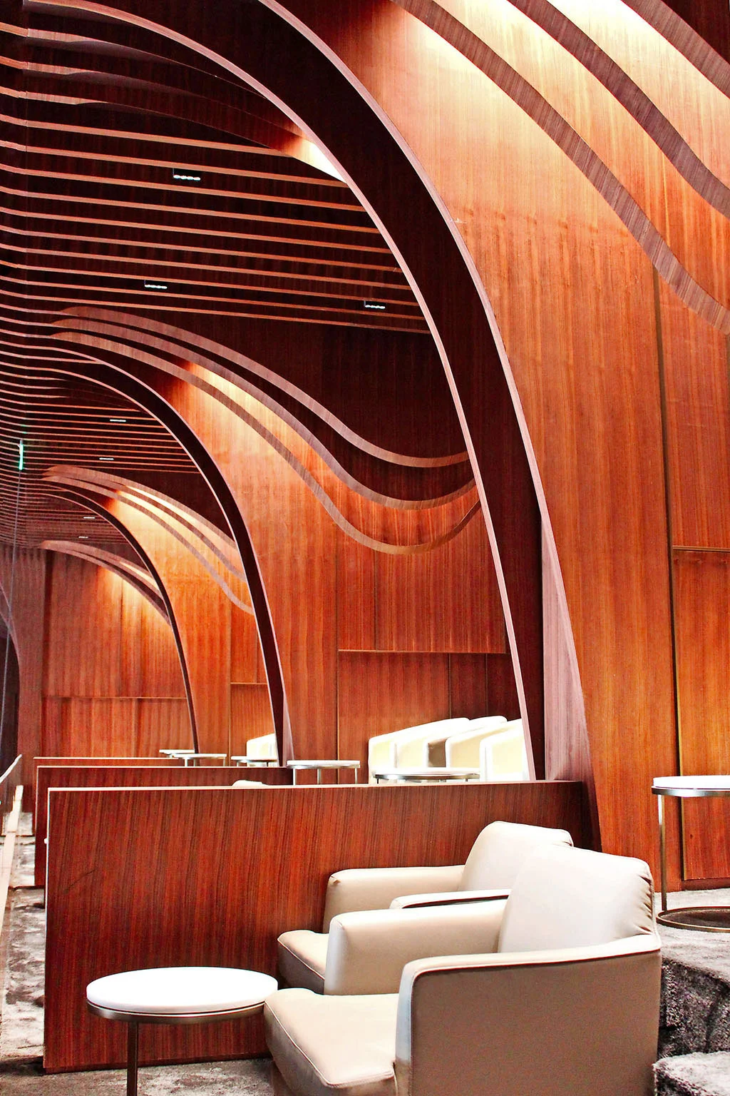 Lounge with curved wooden ribbons forming arches overhead and cream leather armchairs – Maraya Concert Hall, AlUla, Saudi Arabia, 2019 – architecture