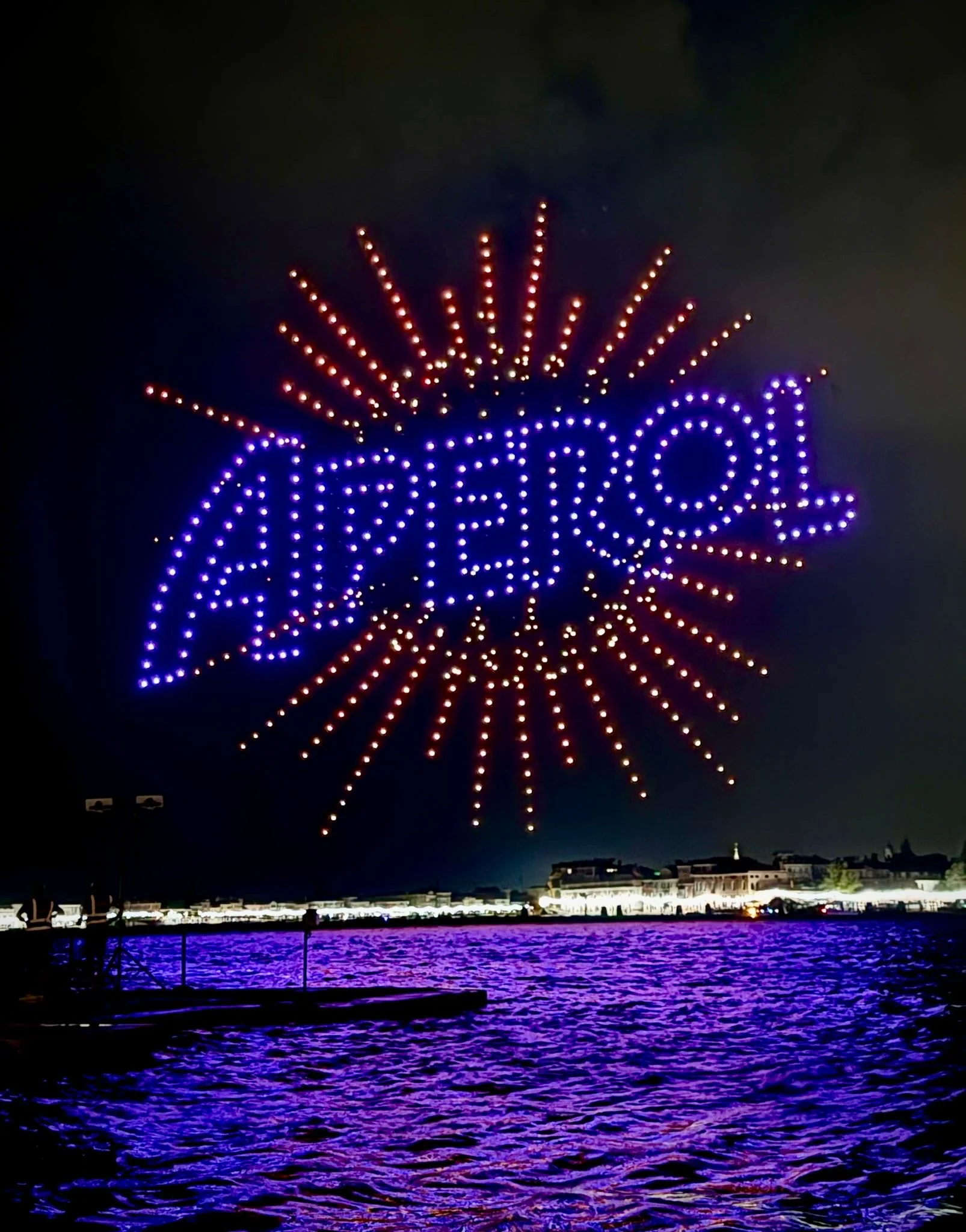 Drones spelling Aperol in blue with orange rays above the lagoon at night – Aperol Redentore Drone Show, Venice, Italy, 2024 – creative direction