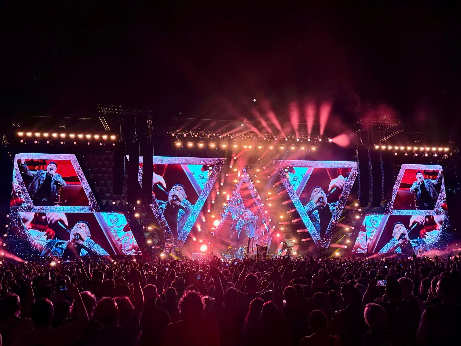 Triangular screens in red and pink light, with spark beams fanning out over the audience – Vasco Rossi Live 2024, Italy – concert stage design