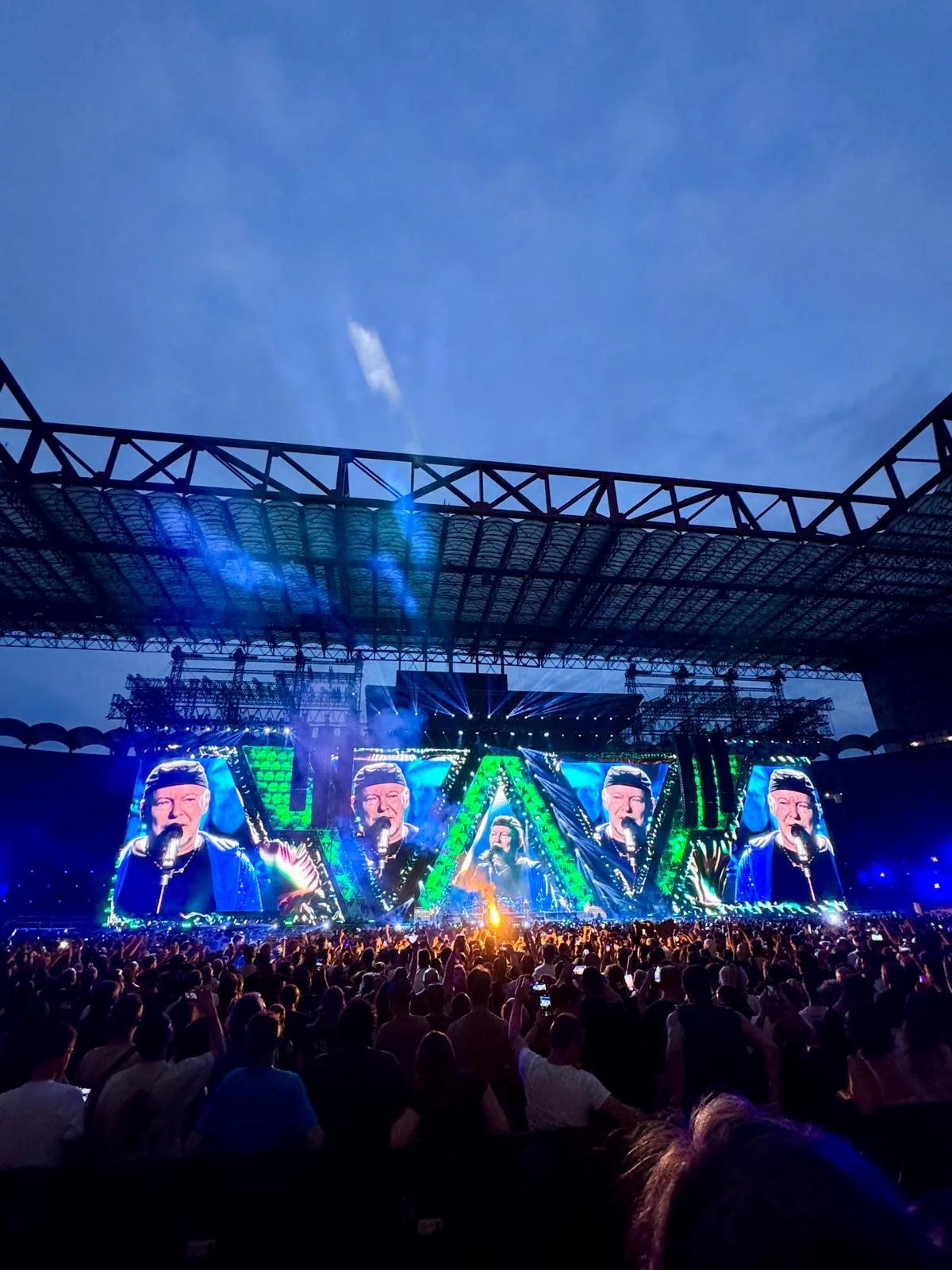 Vertical view of the stage in green light beneath the stadium roof and an evening sky – Vasco Rossi Live 2024, Italy – concert stage design