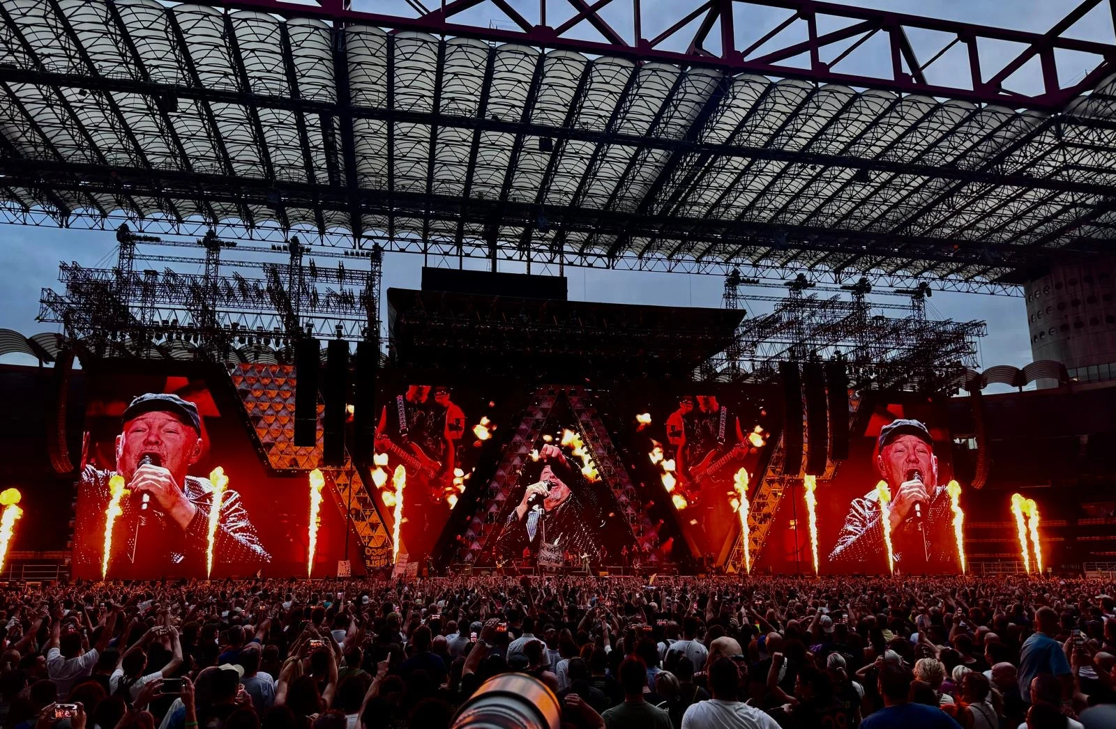 Flame jets firing along the stage front while side screens show the singer, under the stadium roof – Vasco Rossi Live 2024, Italy – concert stage design
