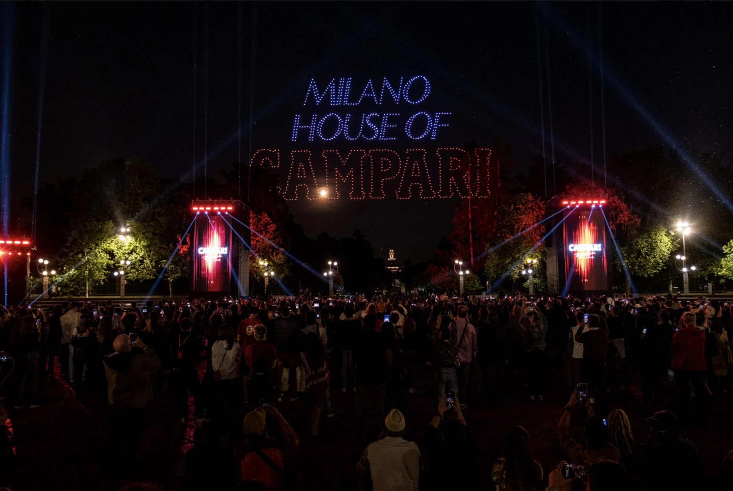 Drones spelling Milano House of Campari in the night sky above the crowd and red-lit Campari towers – Milano House of Campari, Italy, 2023 – event design
