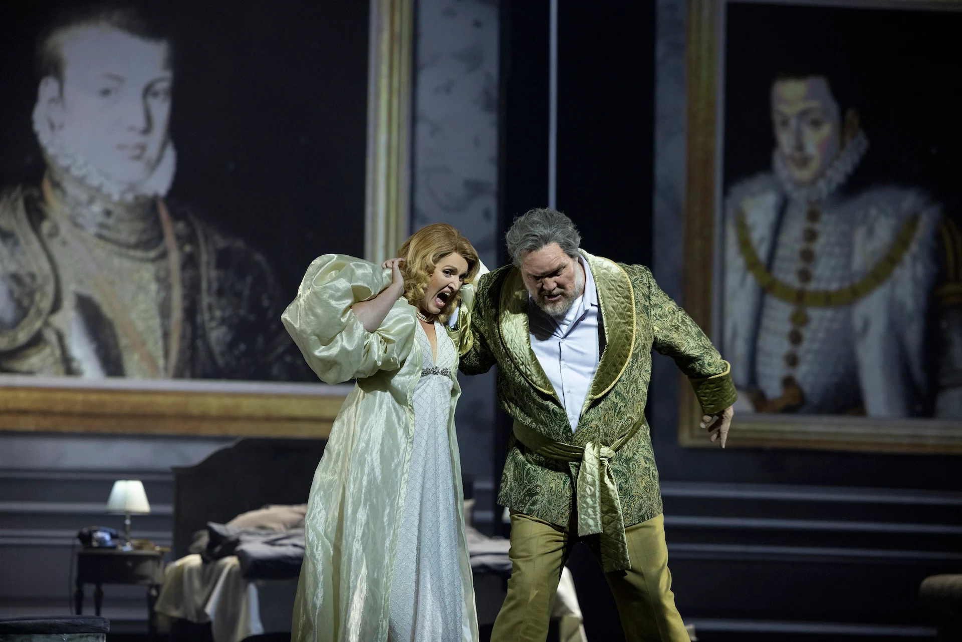 Singer in a pale nightgown recoiling from a man in a green robe, framed Renaissance portraits behind – Don Carlo at the Royal Danish Theatre, Copenhagen, Denmark, 2024 – opera set design