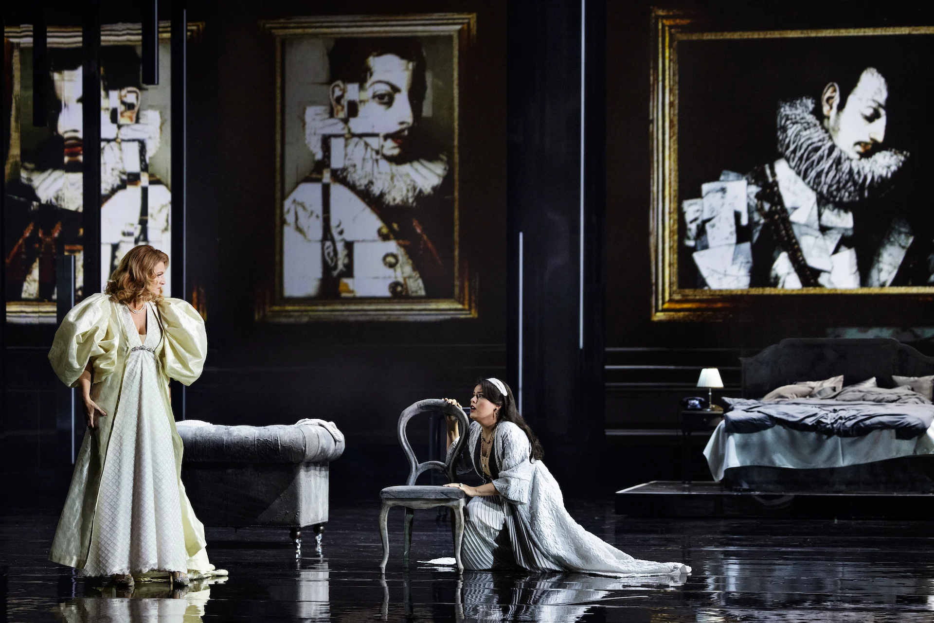 Woman in an ivory gown facing a kneeling woman beside a chair, fragmented portraits in gold frames – Don Carlo at the Royal Danish Theatre, Copenhagen, Denmark, 2024 – opera set design