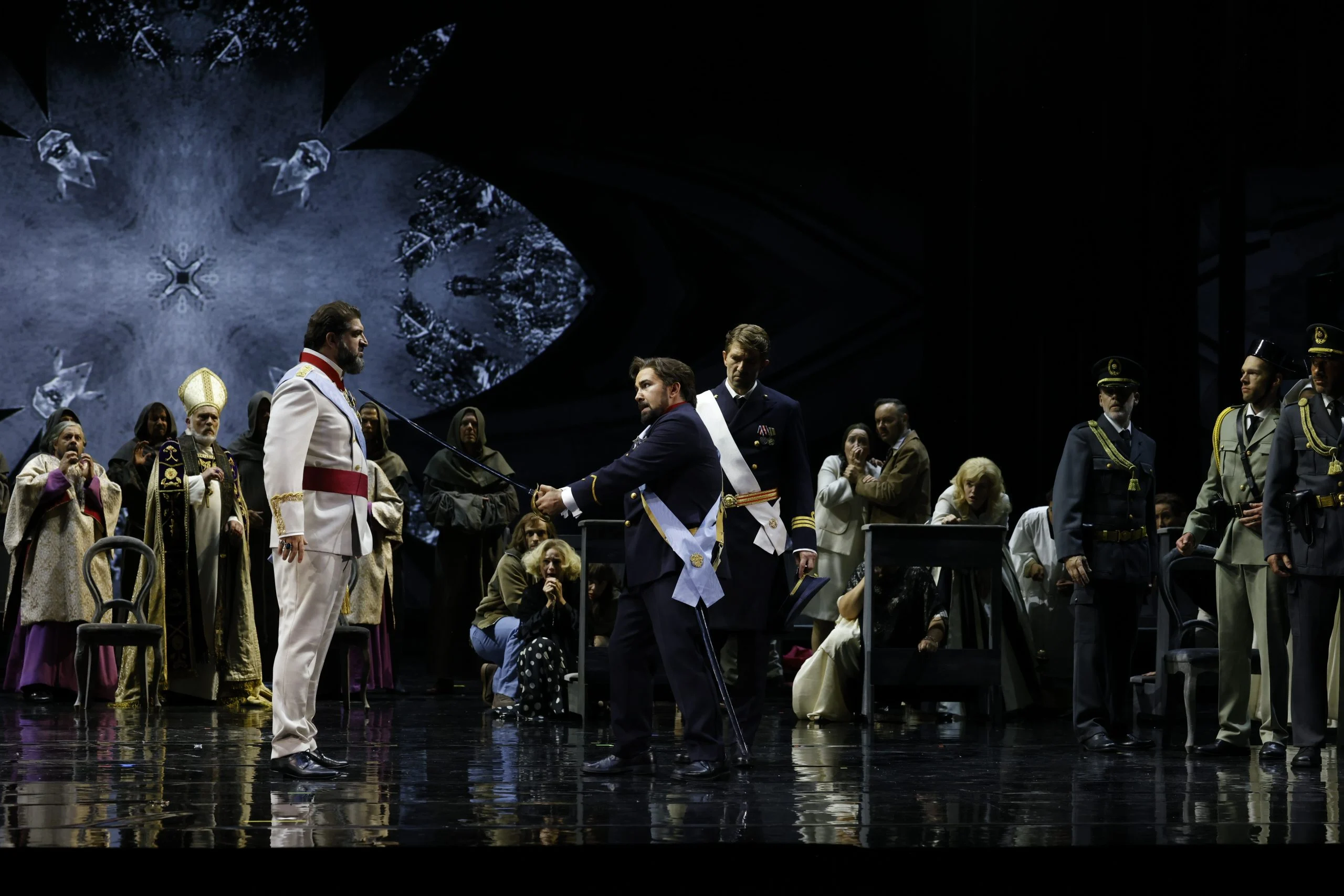 Confrontation between men in uniforms and sashes, clergy and chorus watching, a projected rose window behind – Don Carlo at the Royal Danish Theatre, Copenhagen, Denmark, 2024 – opera set design