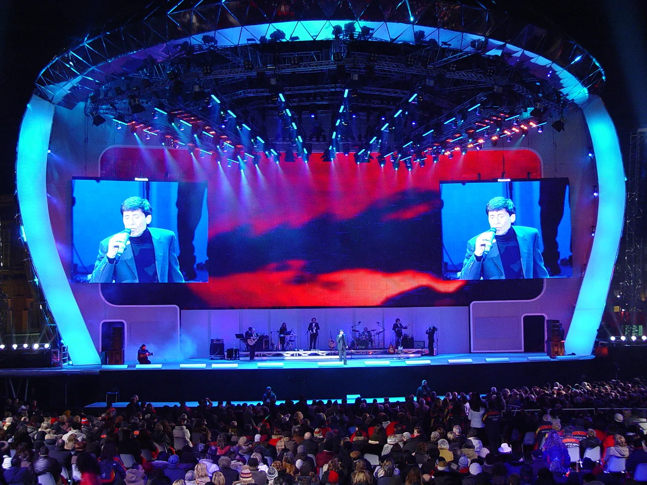 Concert on the Medals Plaza stage: singer on the side screens, red sky graphics and band under the lighting rig – Medals Plaza, Turin 2006 Winter Olympics, Italy – event design