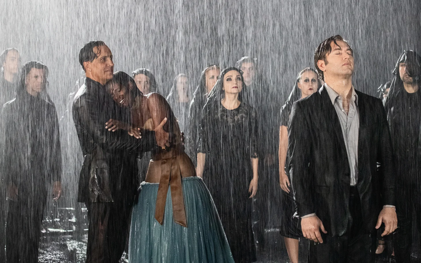 Film still: a couple embracing and a man in a dark suit amid a crowd in heavy rain – The Opera! Arie per un'Eclissi at Rome Film Festival, Italy, 2024 – set design