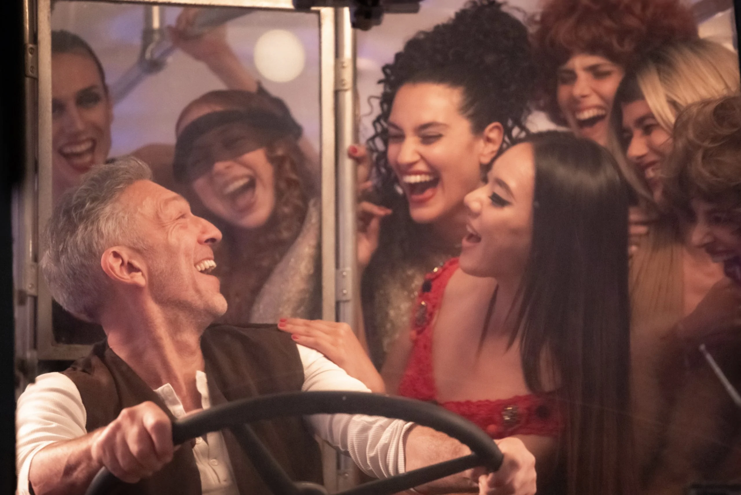 Film still: laughing performers crowded around a driver at the wheel of a bus – The Opera! Arie per un'Eclissi at Rome Film Festival, Italy, 2024 – set design