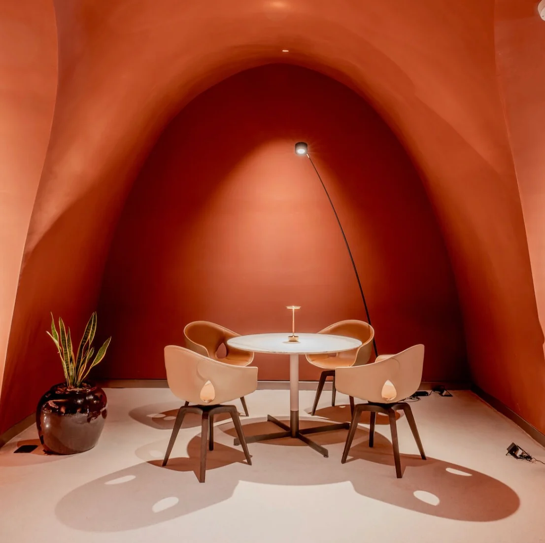 Four leather chairs around a round table in a terracotta alcove lit by an arc floor lamp – King Fahad Chair for Poltrona Frau, Riyadh, Saudi Arabia, 2024 – product design