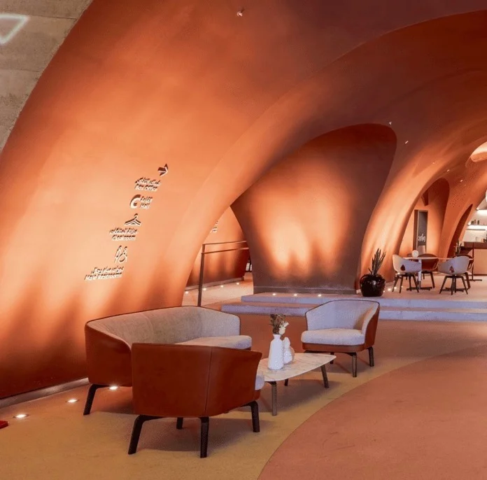 Leather armchairs and sofa in a terracotta vaulted lounge, with wall signage and a café beyond – King Fahad Chair for Poltrona Frau, Riyadh, Saudi Arabia, 2024 – product design