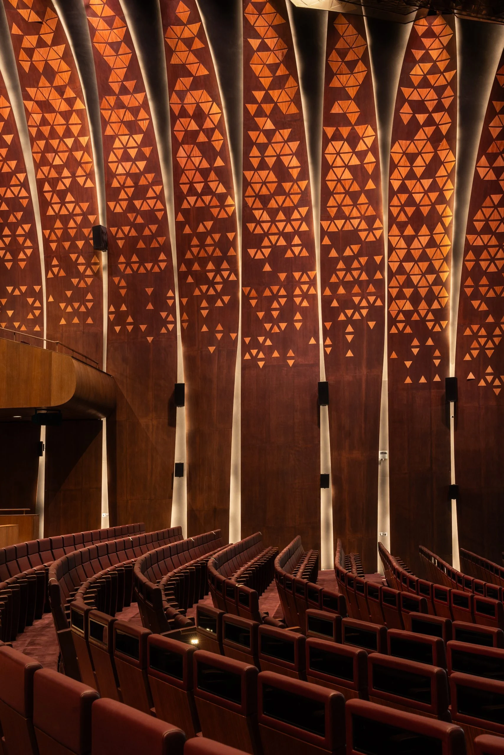 Rows of King Fahad chairs in the auditorium below wall panels with a triangular wood pattern – King Fahad Chair for Poltrona Frau, Riyadh, Saudi Arabia, 2024 – product design