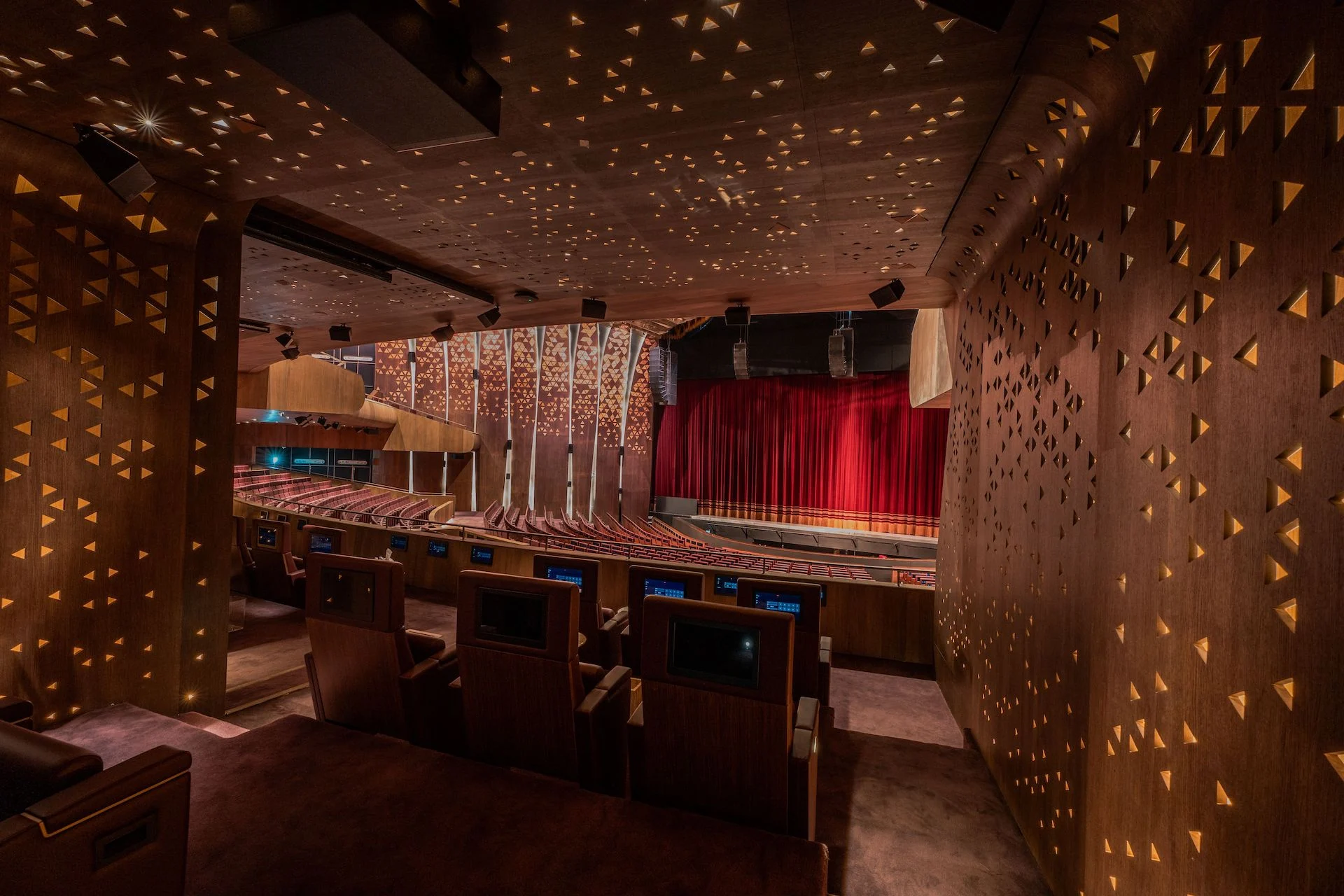 Back of King Fahad chairs with integrated screens, seen from a box towards the red stage curtain – King Fahad Chair for Poltrona Frau, Riyadh, Saudi Arabia, 2024 – product design