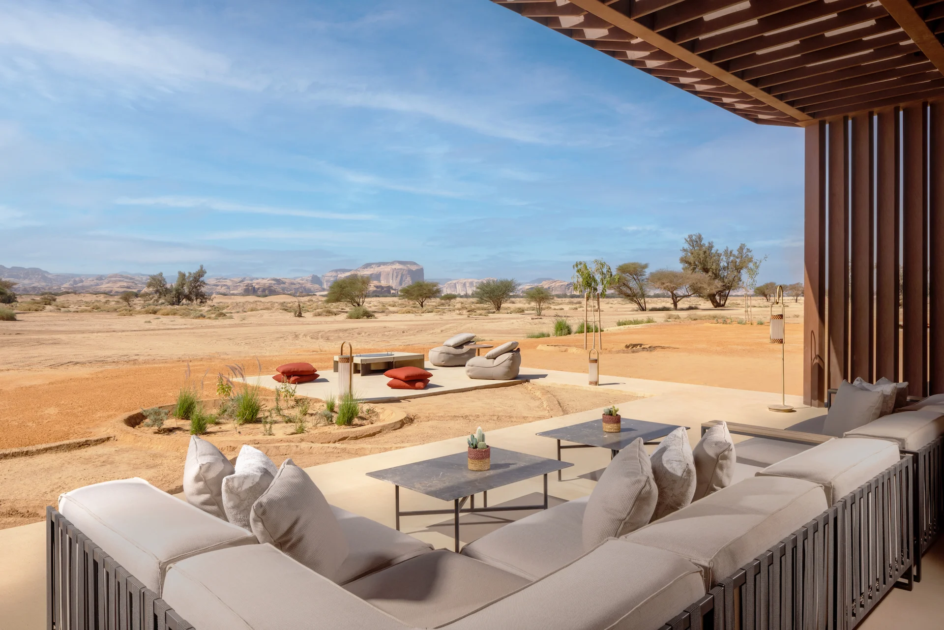 Shaded terrace with a sofa and low tables overlooking the desert and a fire pit lounge – The Chedi Hegra, AlUla, Saudi Arabia, 2024 – hotel architecture