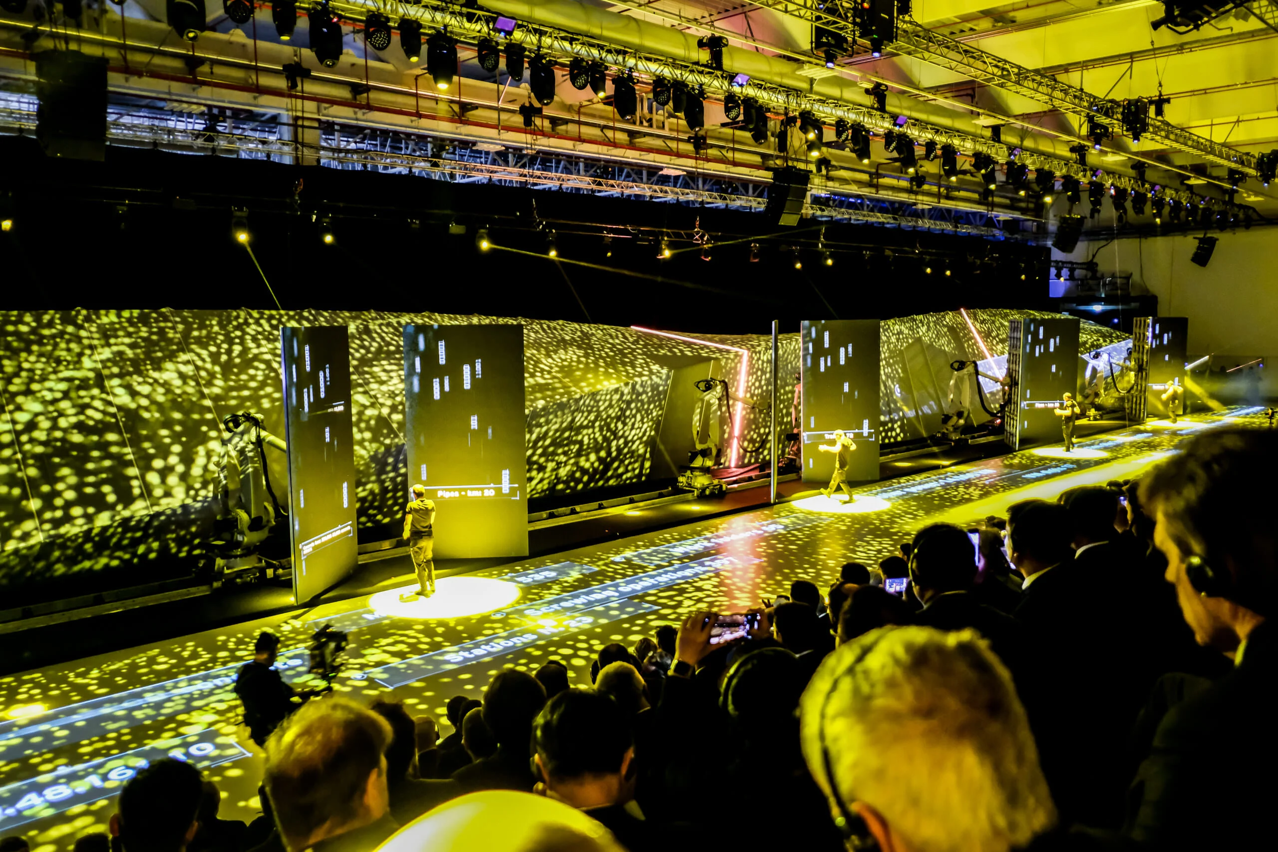 Audience watching the show along the stage, robots and screens in a field of yellow projected light – Lamborghini Urus World Premiere, Sant'Agata Bolognese, Italy, 2017 – event design