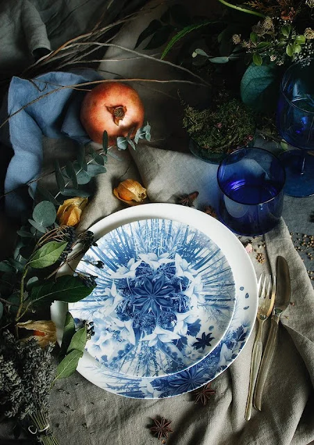 Top view of blue-decorated plates with a pomegranate, herbs and a blue glass on rumpled linen – Botanica Tableware for Bitossi Home, 2017 – product design