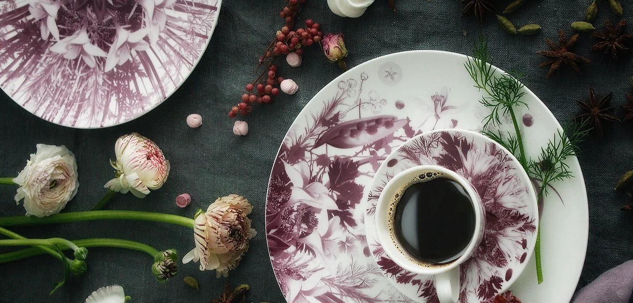 Plum botanical cup and saucer of coffee on a decorated plate, with ranunculus and berries on dark cloth – Botanica Tableware for Bitossi Home, 2017 – product design