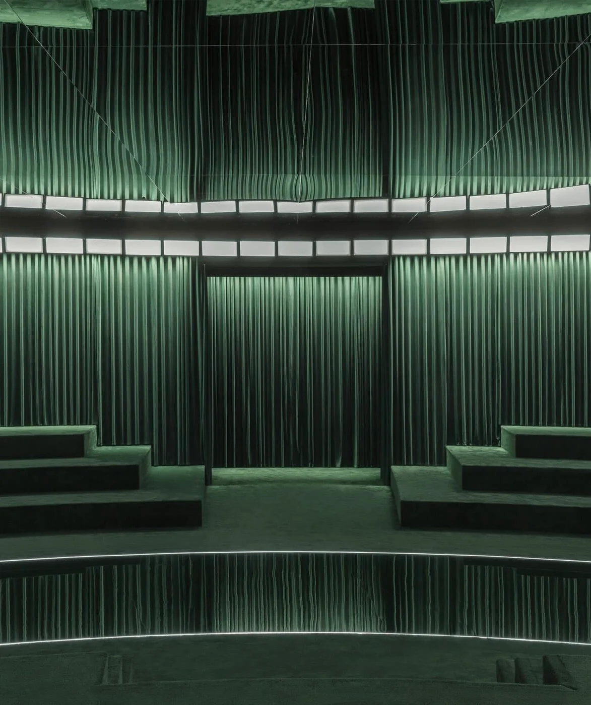 Frontal view of the curtained runway entrance flanked by green velvet bleachers – Gucci Fall/Winter 2025, Milan, Italy – fashion show set design