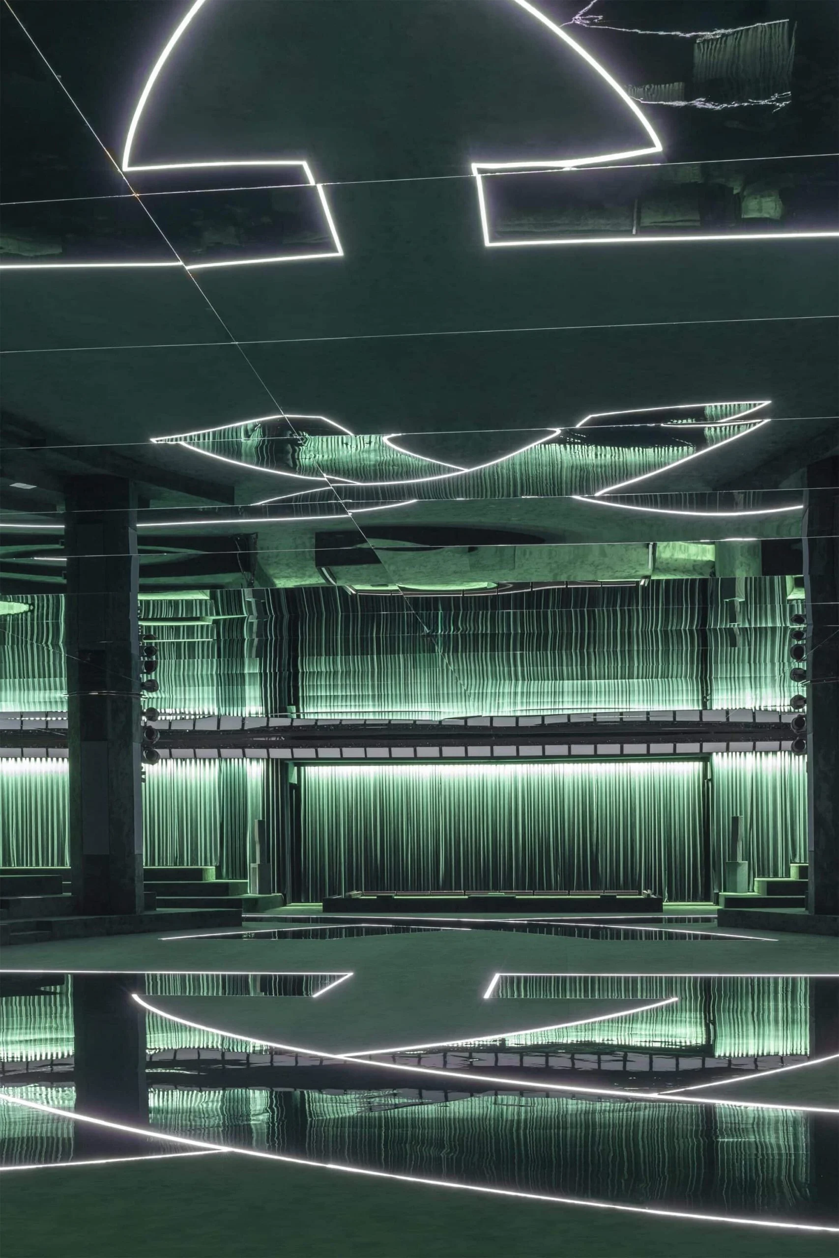 Vertical view of the green show venue: neon arcs on the mirrored ceiling reflected in the glossy floor – Gucci Fall/Winter 2025, Milan, Italy – fashion show set design