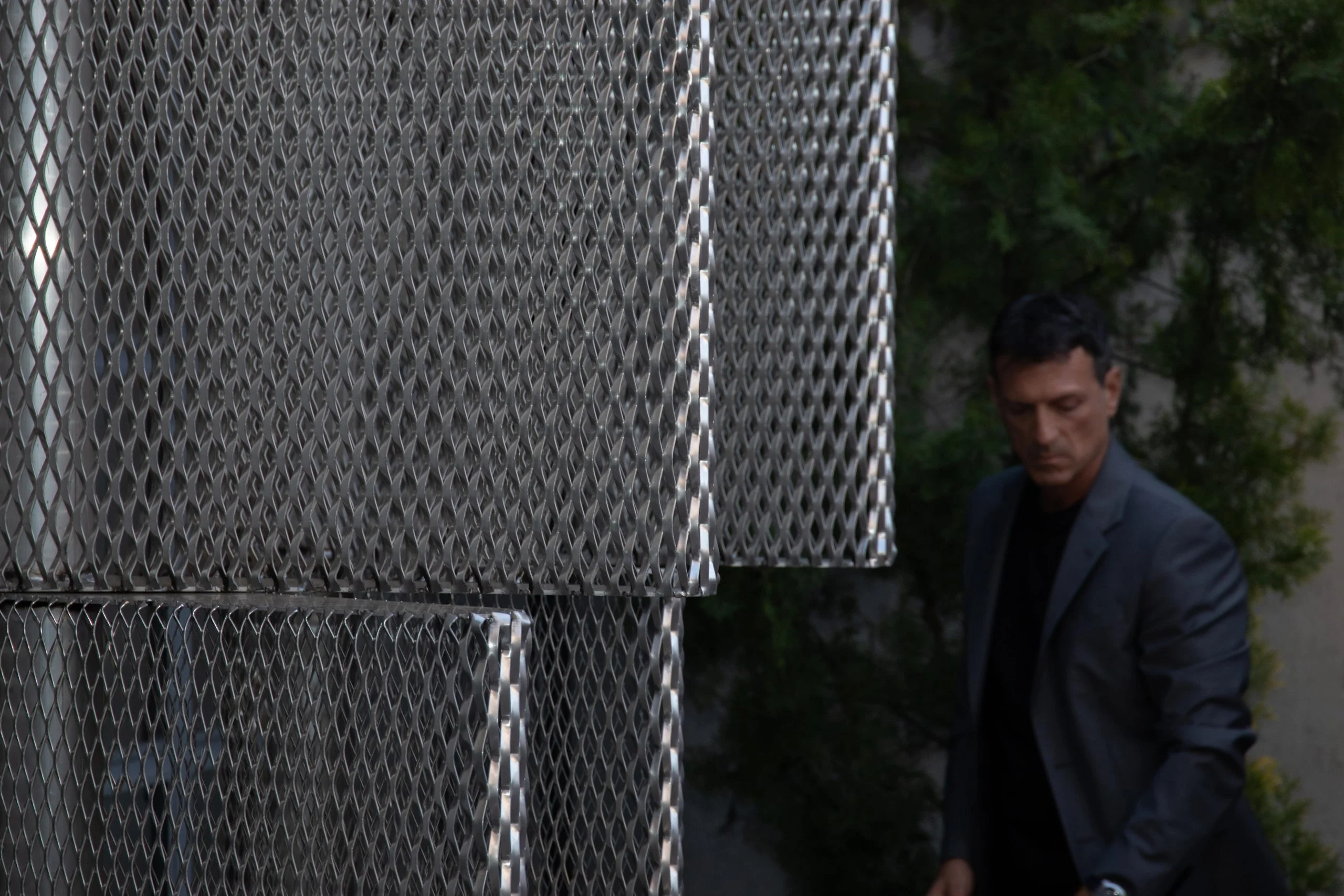 Stacked silver expanded mesh boxes in the garden, a guest walking past – Everything Is a Party at Fuorisalone, Milan, Italy, 2025 – event design